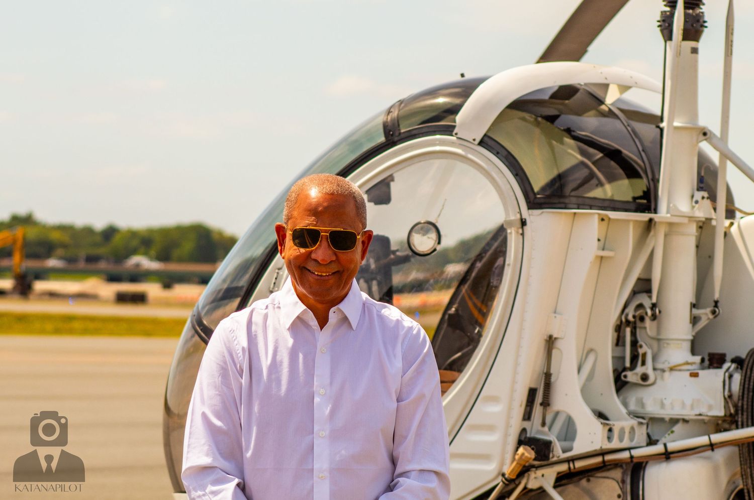 Aviation personnel gathered near parked helicopter on sunny tarmac.