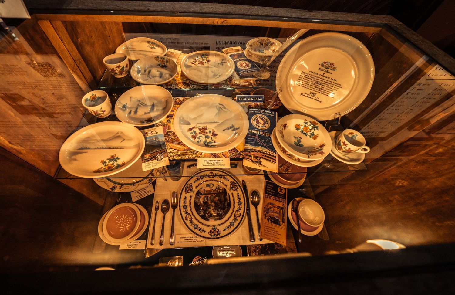 Extensive collection of vintage railroad china and dinnerware displayed in museum cases with warm lighting.