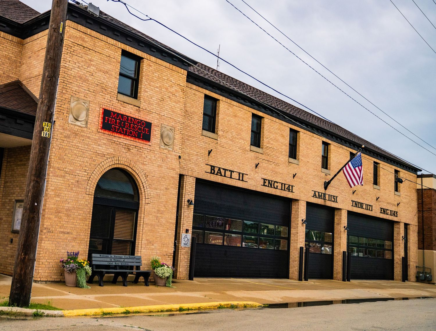 Long brick commercial building facade with American flag and storefront windows.