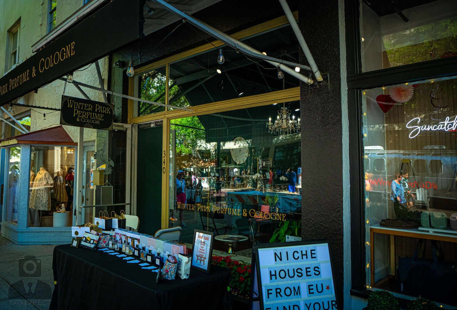 Dark storefront with business hours sign and reflective windows showing street scene.