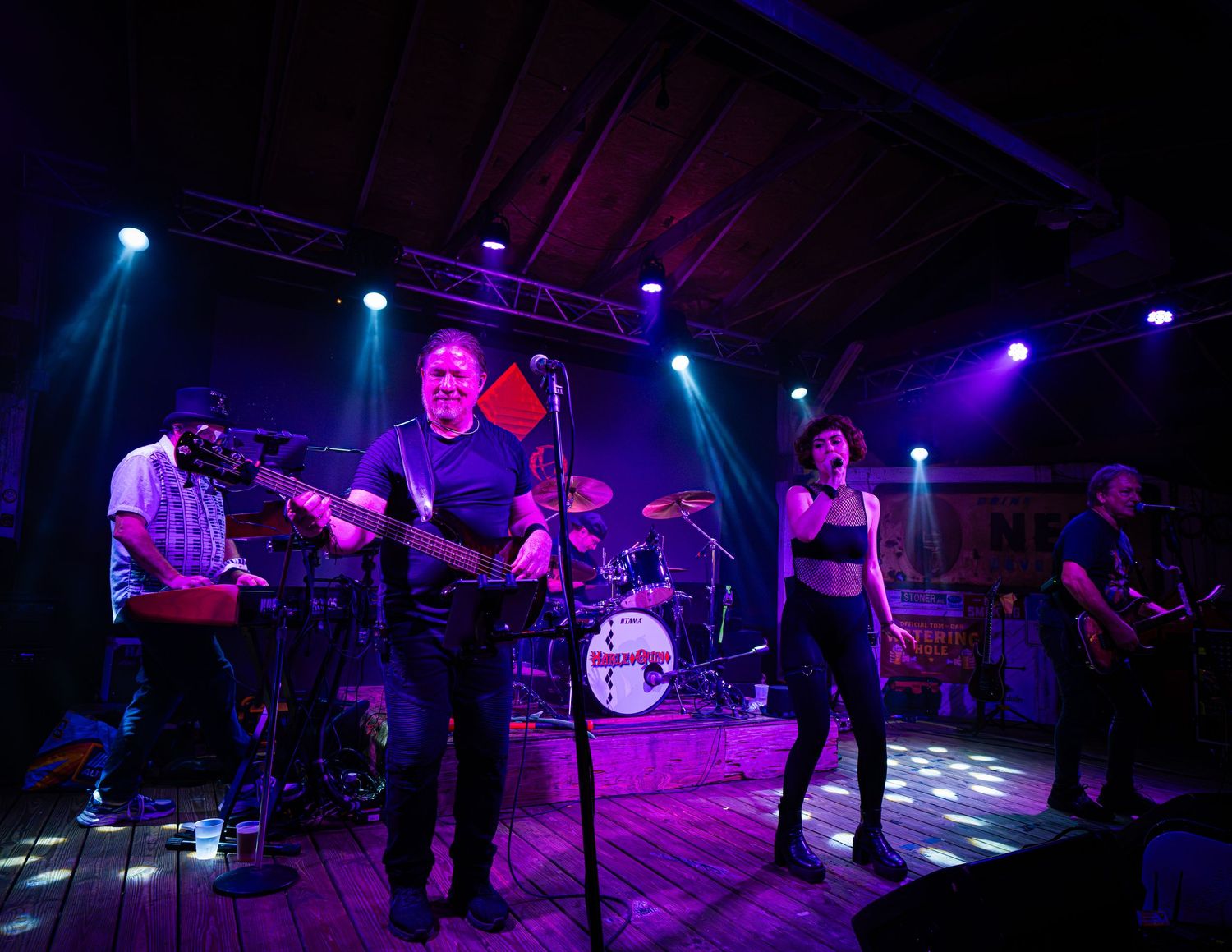 Wide shot of concert venue with purple lighting and band performing on stage.