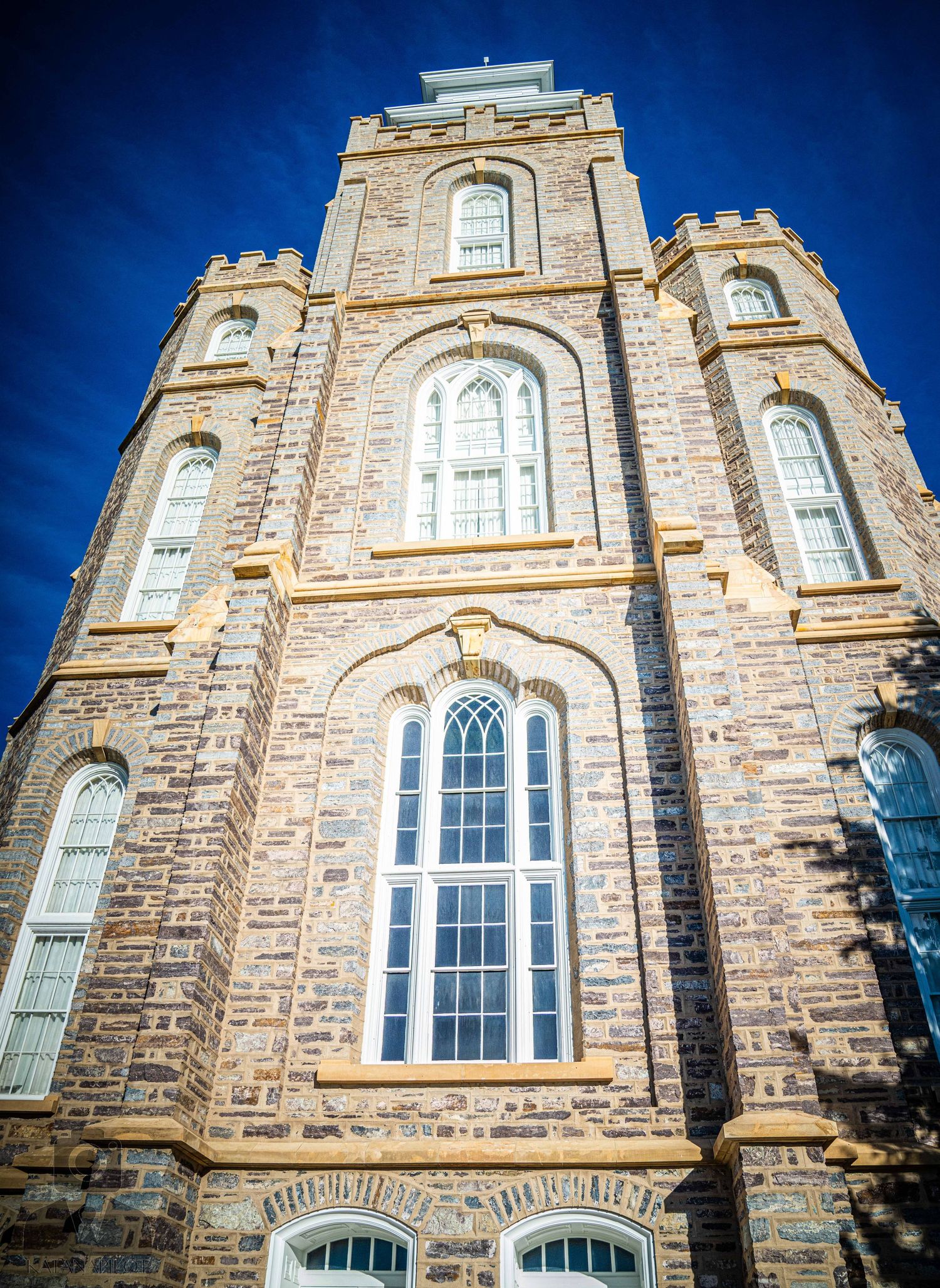 Gothic revival architecture featuring symmetrical stone towers and arched windows against deep blue sky.