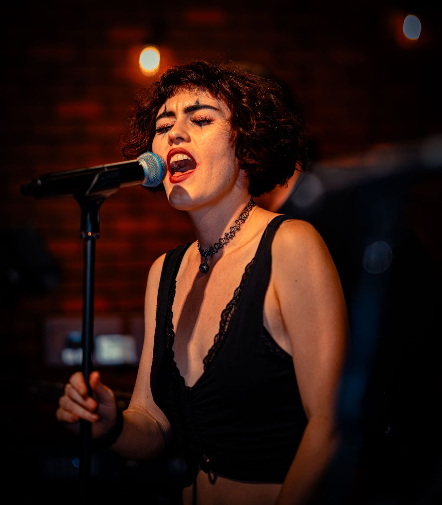 Singer performing passionately on stage in dark venue with dramatic lighting.