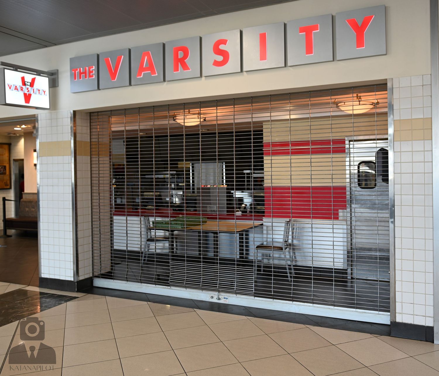 The Varsity restaurant storefront with red lettering and metal security gate down.