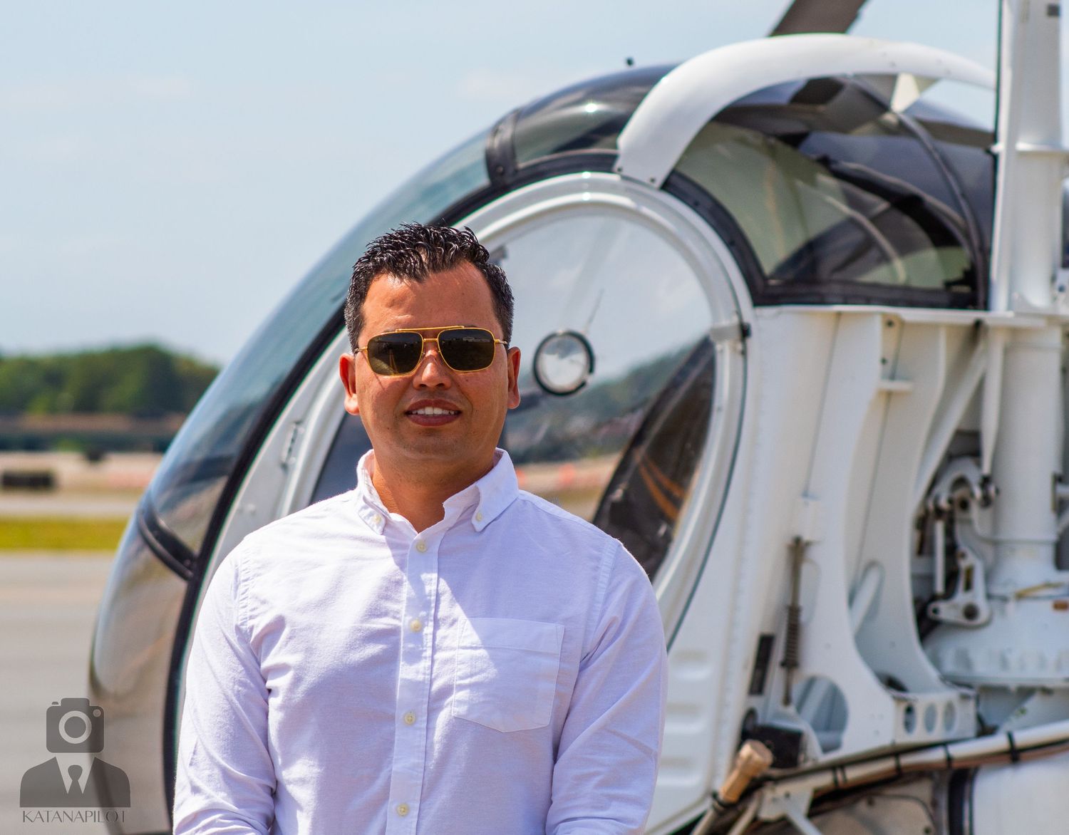 White helicopter parked on airport tarmac during sunny day.