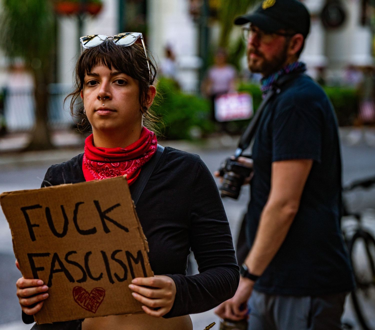 Protester holds a cardboard sign with anti-fascist message during street demonstration.