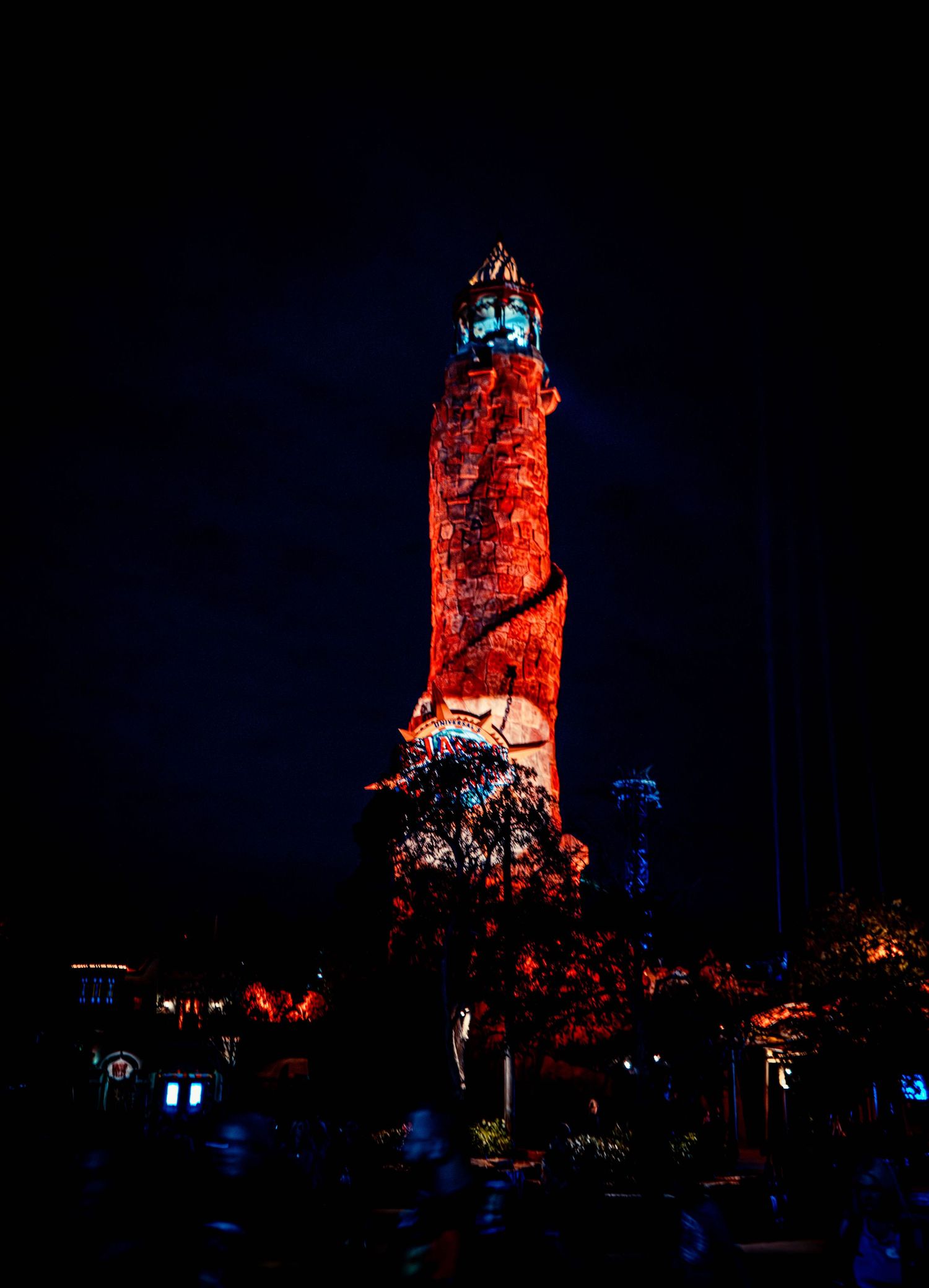 A lighthouse illuminated in dramatic red lighting against a dark night sky stands tall as a striking landmark.