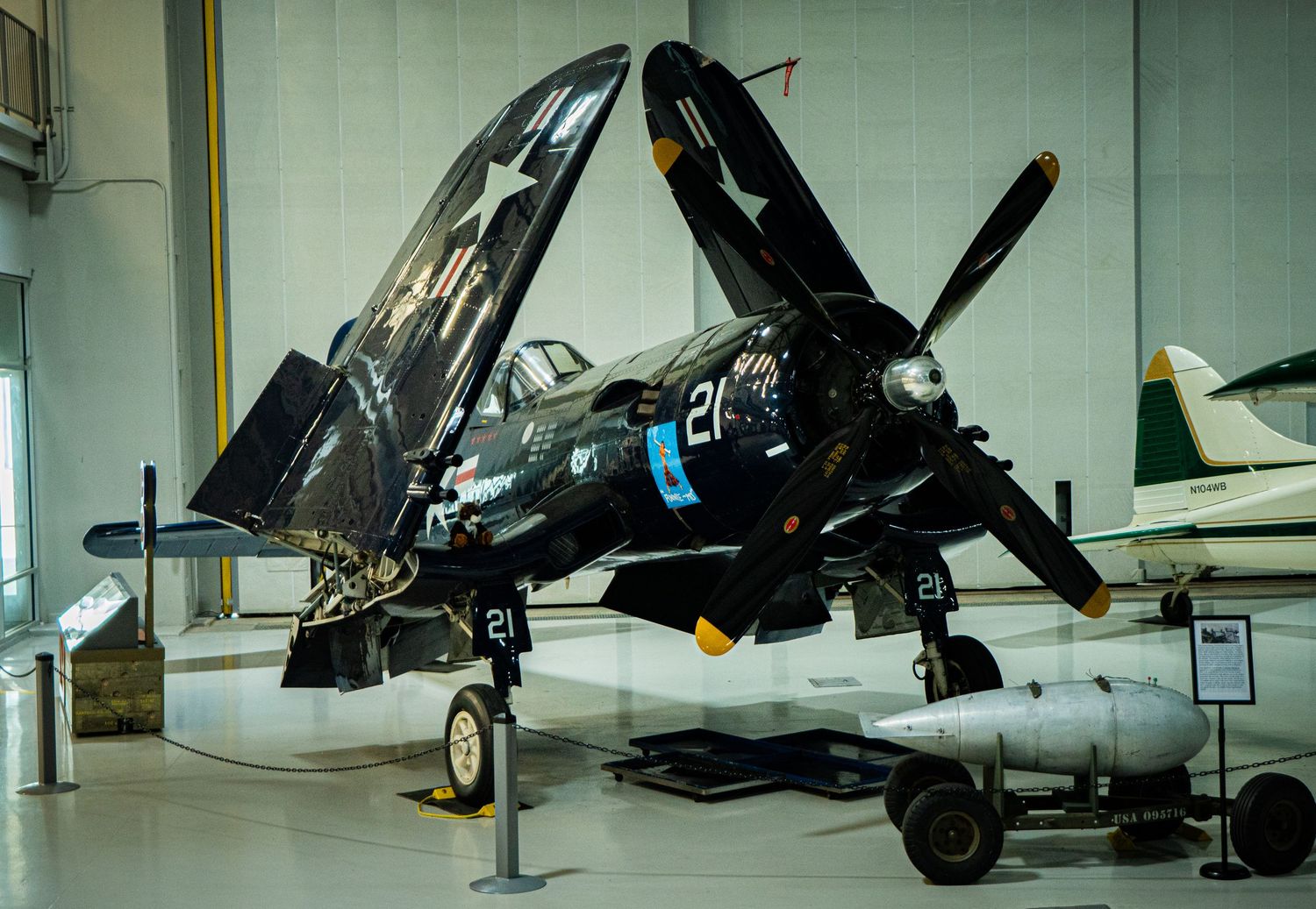 Dark painted WWII Vought F4U Corsair fighter aircraft number 21 displayed in aviation museum.