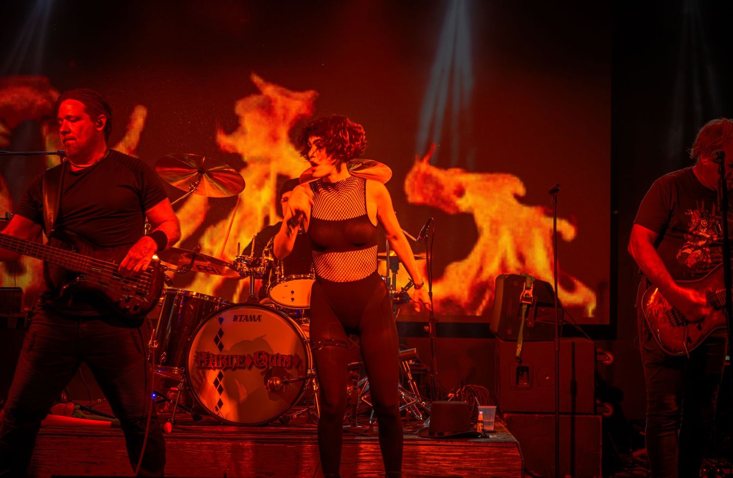 Live music performance captured in vibrant red stage lighting with dynamic movement.