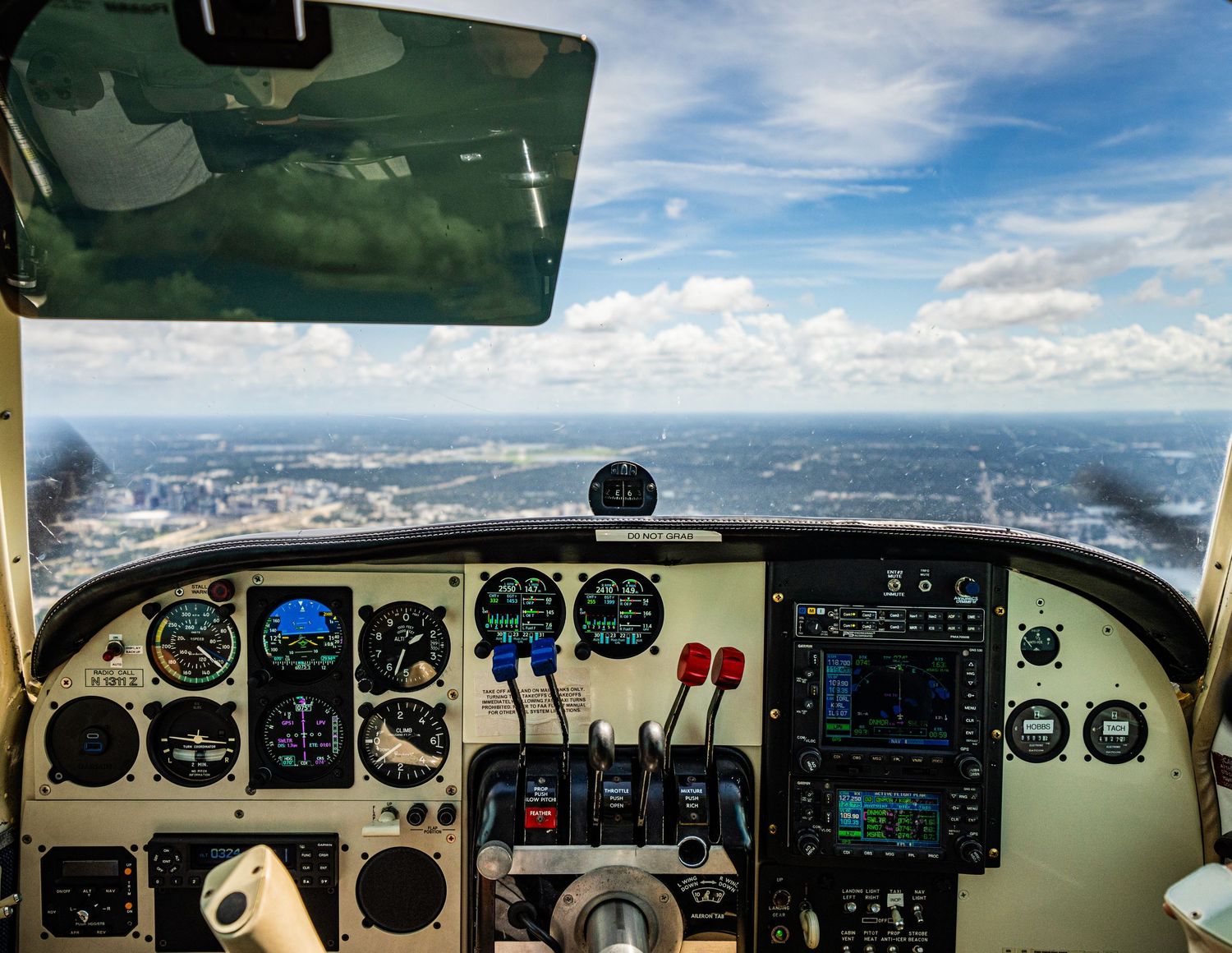 Cockpit view from airplane showing flight instruments and horizon through windshield.