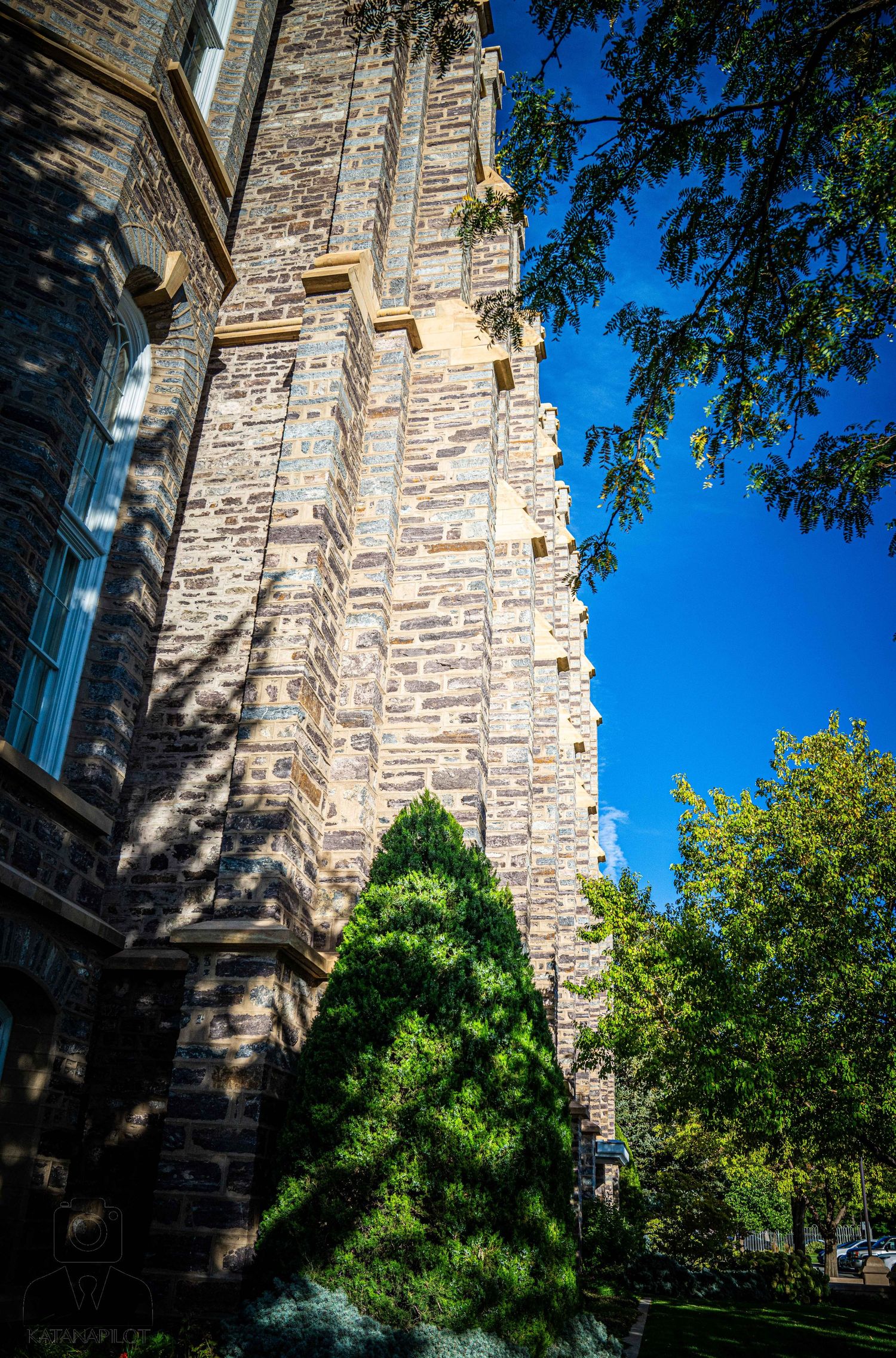 Sunlit stone facade showing detailed masonry work and architectural elements against blue sky.