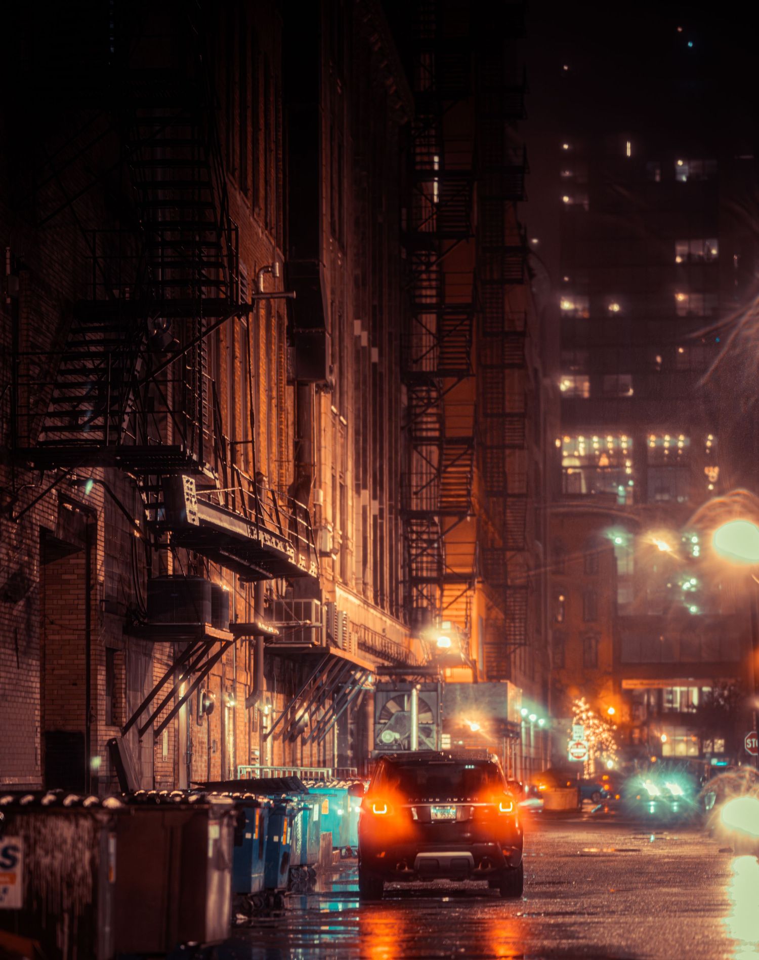 Rainy night street scene with neon lights reflecting off wet pavement in an urban setting.