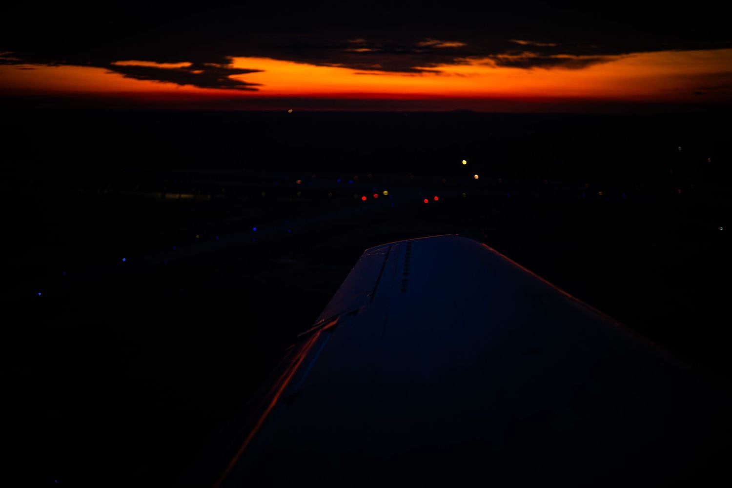 Silhouetted mountain peaks against a vibrant orange and red sunset sky with dark clouds.