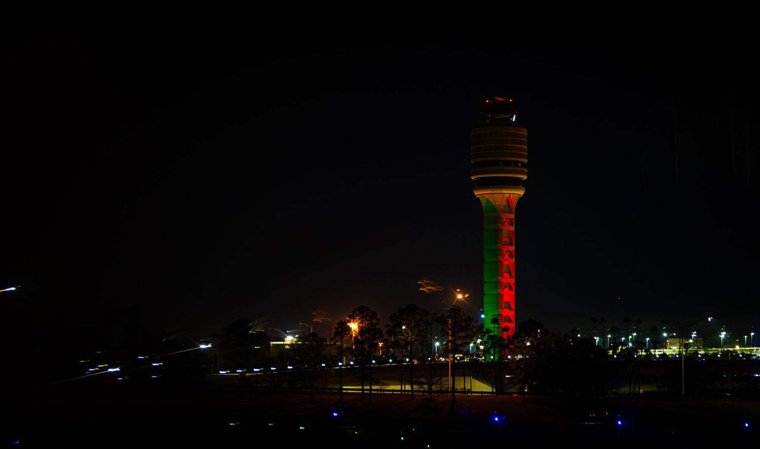 Illuminated cityscape at night with tall buildings and structures creating a glowing skyline against the dark sky.