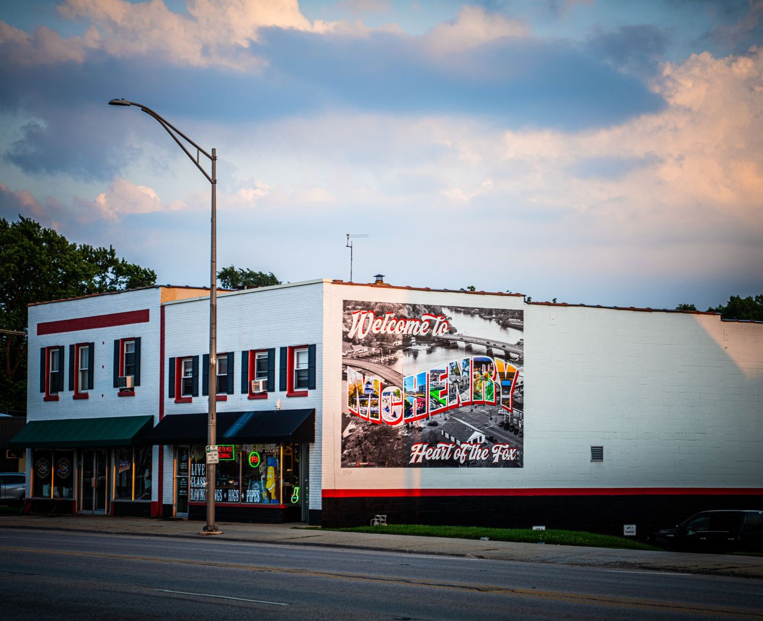 Two-story commercial building with vintage-style billboard on white wall during sunset.