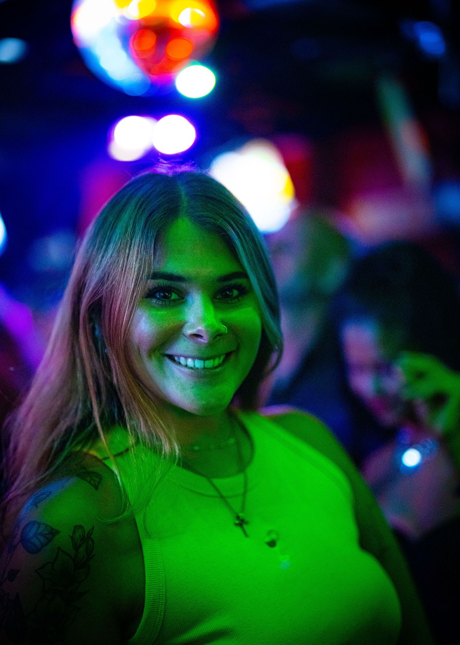 Vibrant green stage lighting creates an atmospheric glow at a nightclub event.