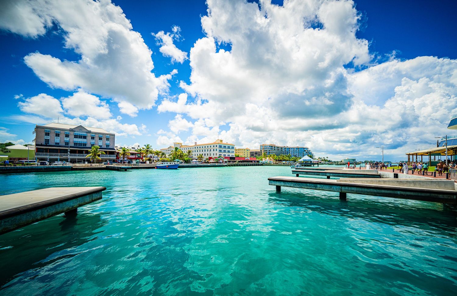 Turquoise waters of a tropical Caribbean harbor with colorful waterfront buildings under dramatic blue skies.