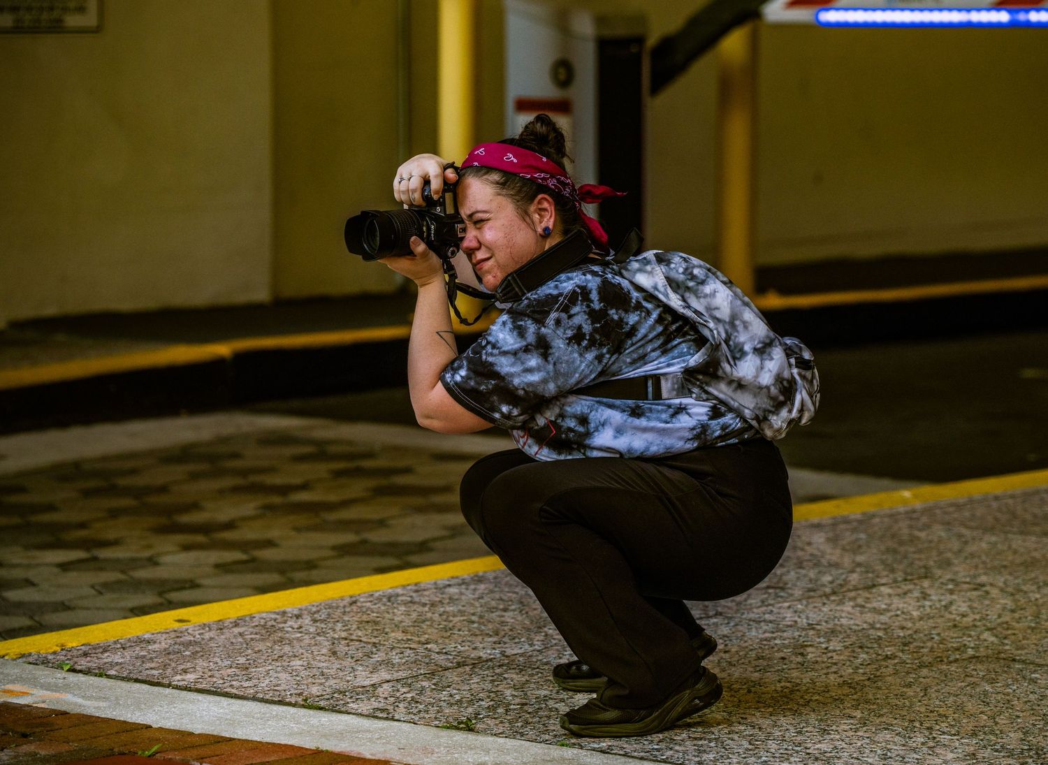 Photographer in urban setting crouches to take a low-angle shot at night.