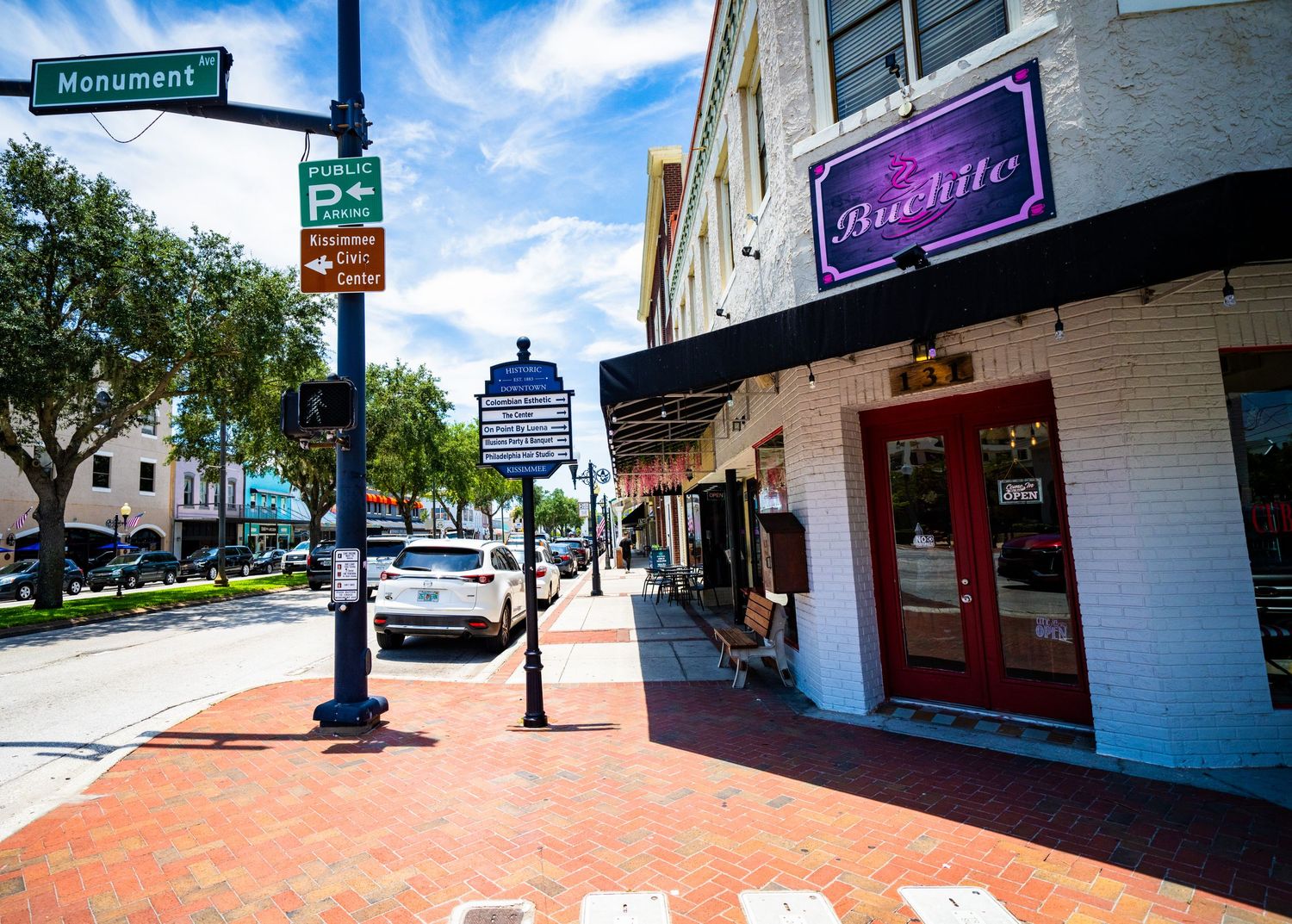 Historic downtown street view with brick sidewalks and storefronts under bright blue sky.