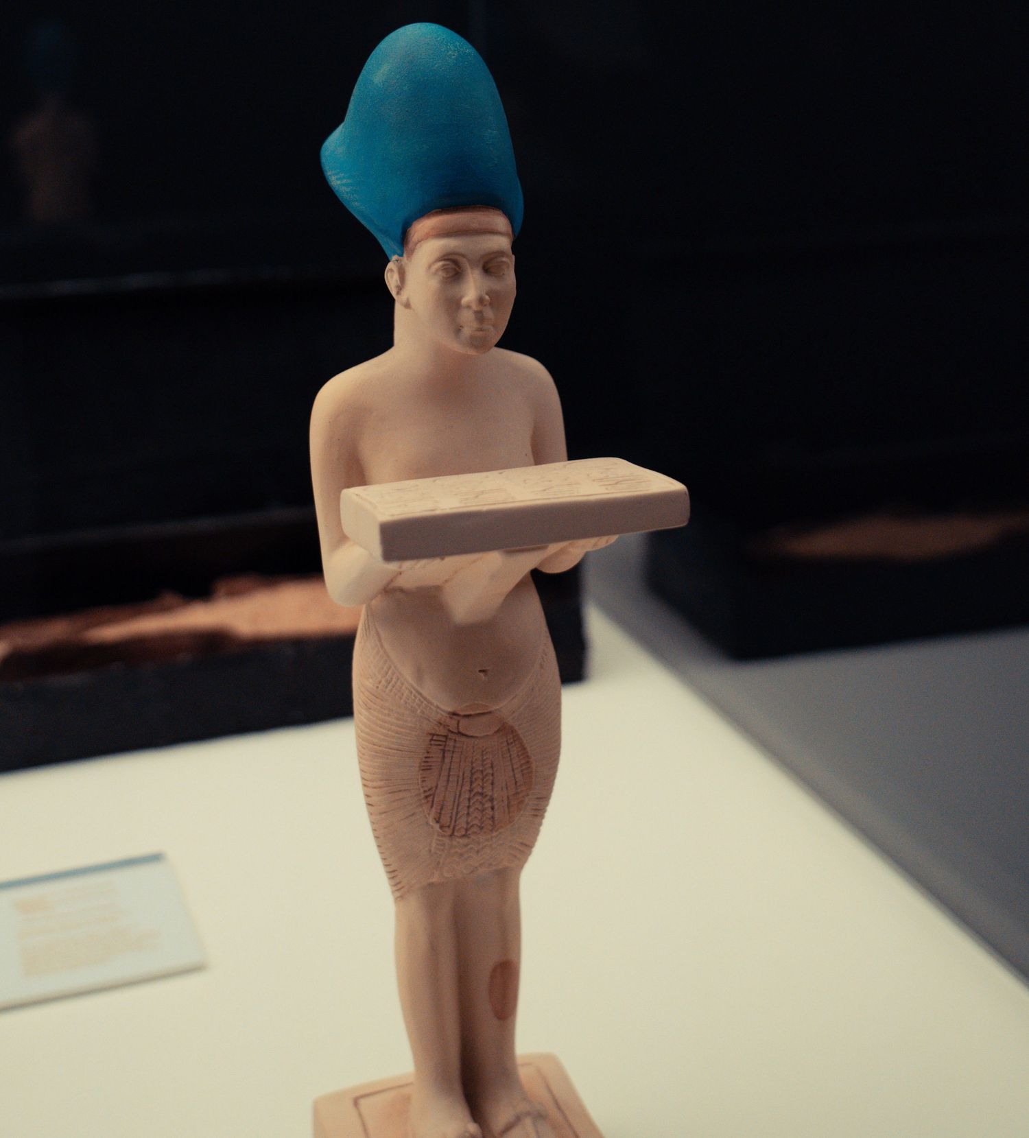 Ancient Egyptian figurines displayed on white museum pedestals.