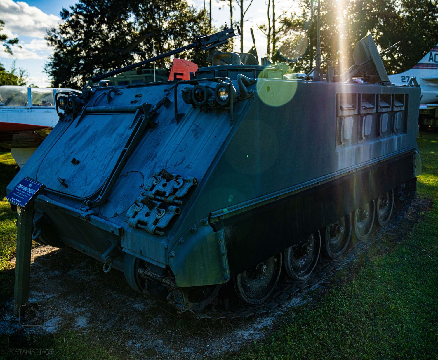 Line of armored personnel carriers and tanks exhibited at a military museum.