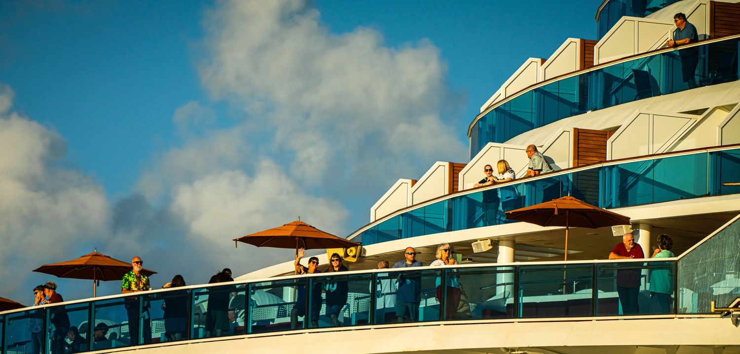 A series of six luxury cruise ship balconies with white railings against a blue sky background.