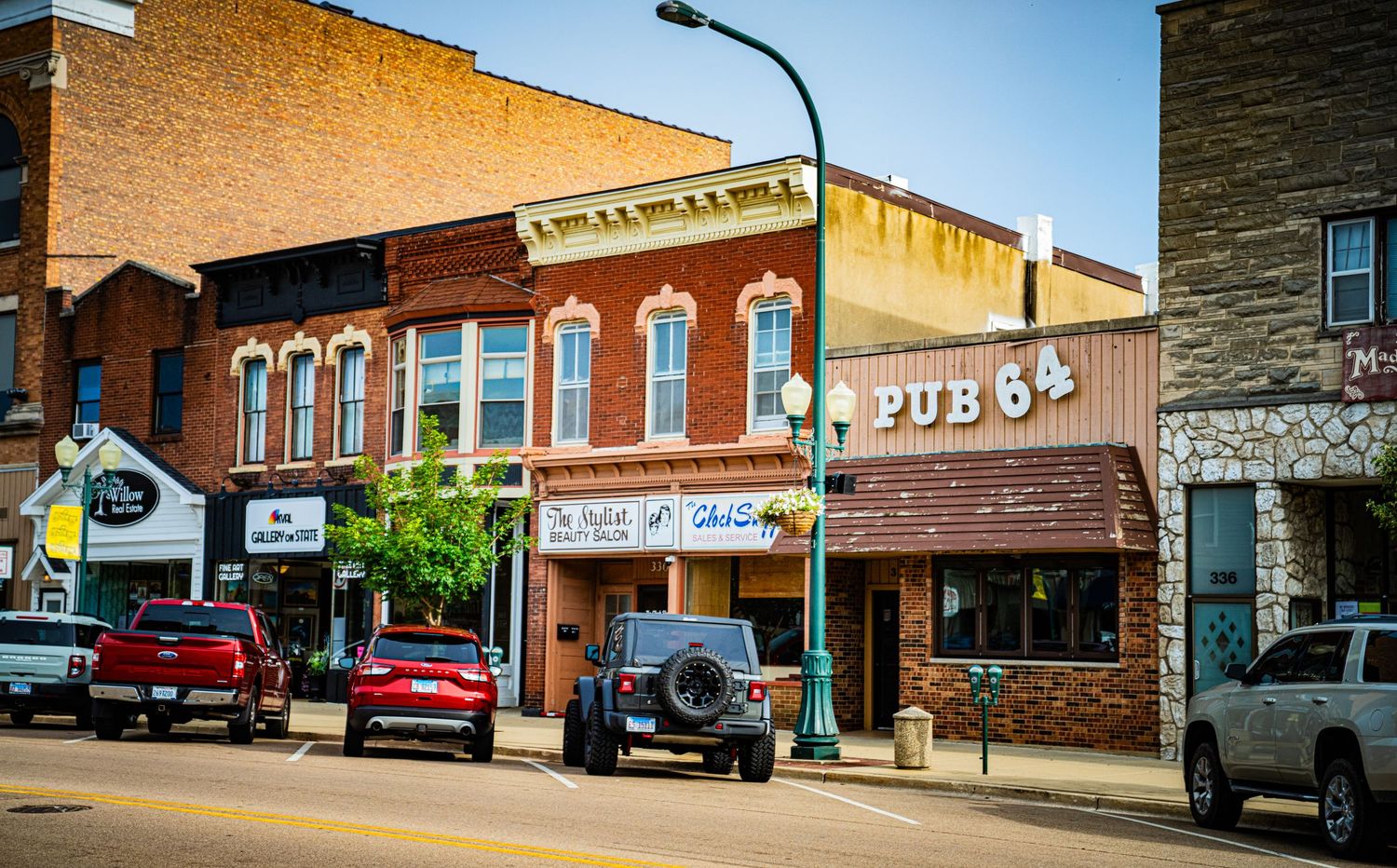 Historic small town main street with brick buildings and vintage storefronts under blue sky.