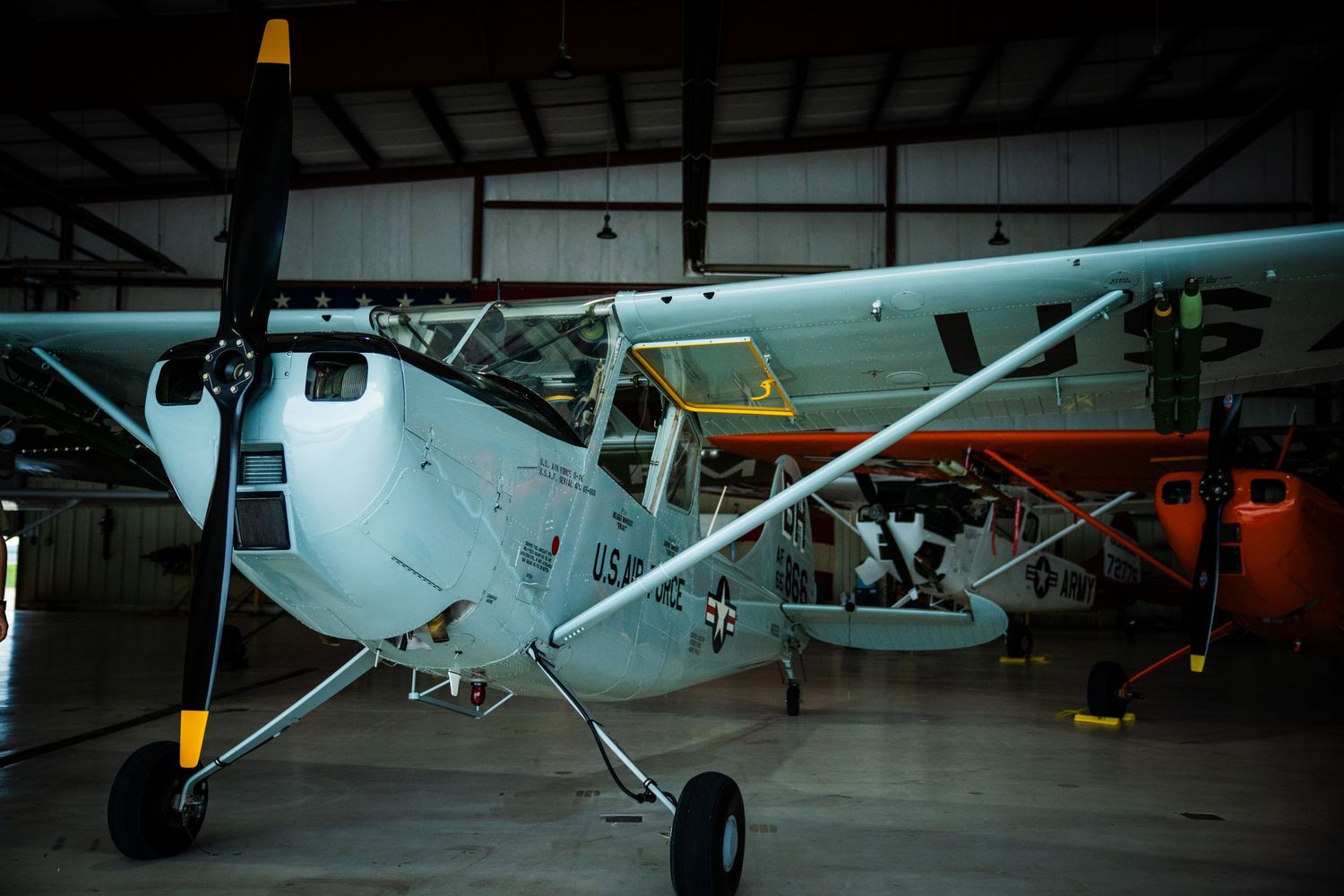 Private planes parked in a dark hangar with maintenance equipment and tools visible.