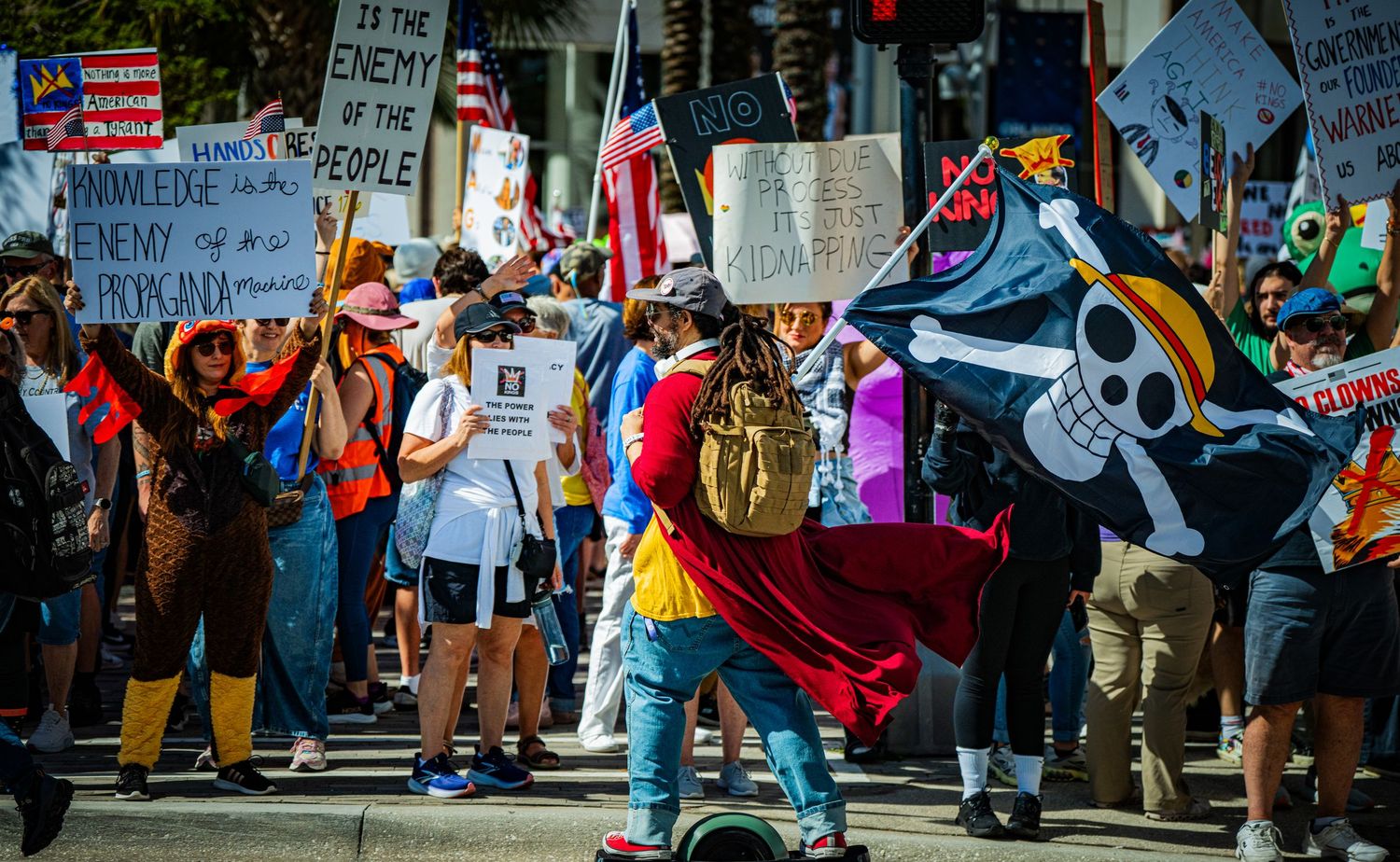 Protest signs and flags wave during a street demonstration against political issues.