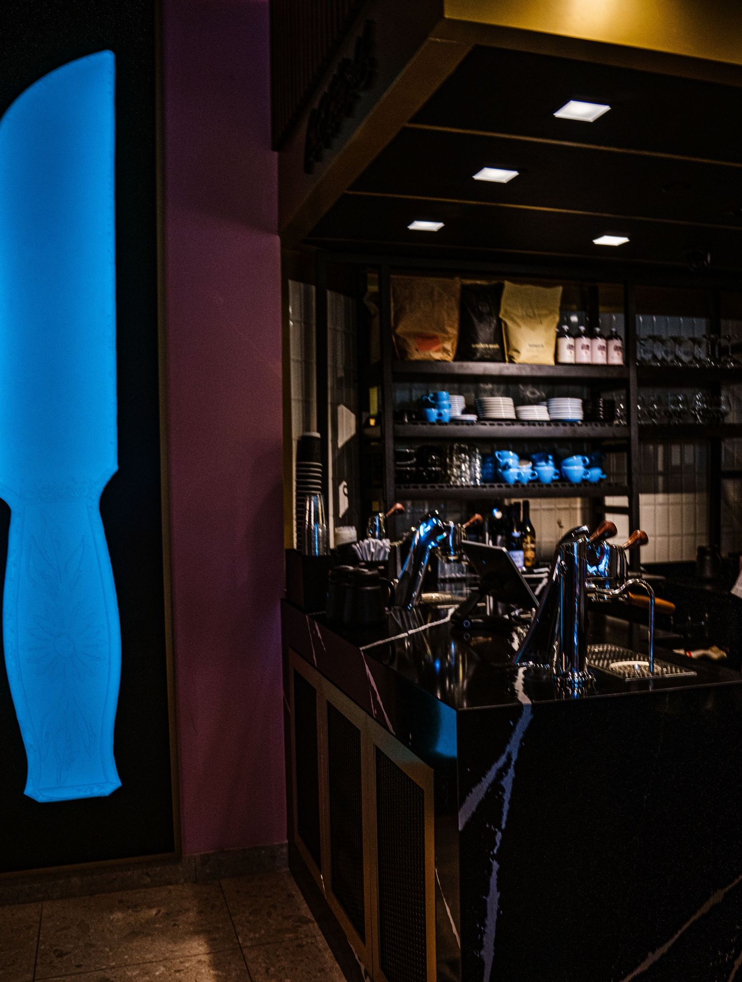 Dimly lit restaurant interior with blue accent lighting and wooden furnishings.