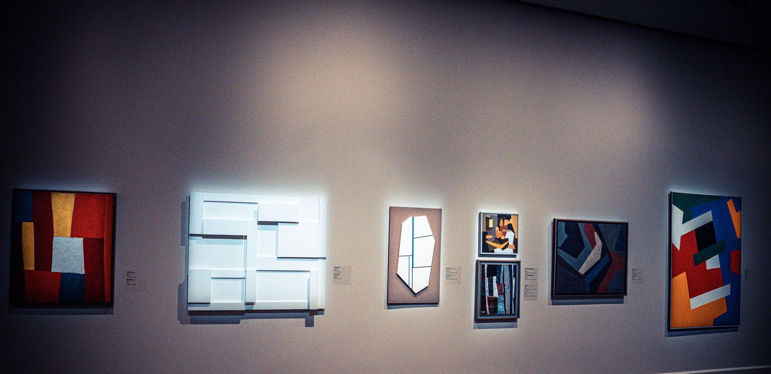 Art gallery hallway with evenly spaced photographs mounted on white walls under spotlights.