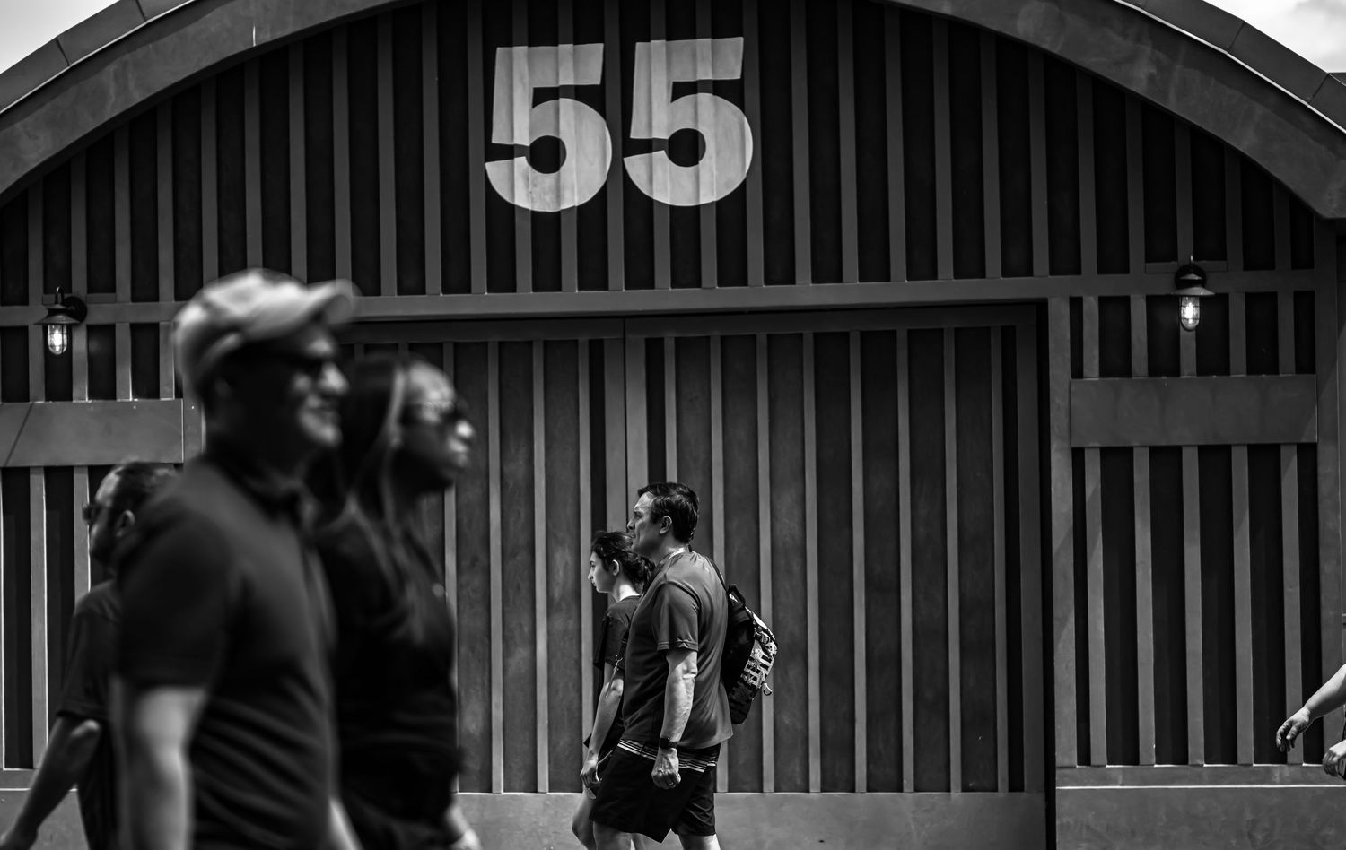 Black and white photo of people standing outside a building with number 55 displayed on the curved facade.