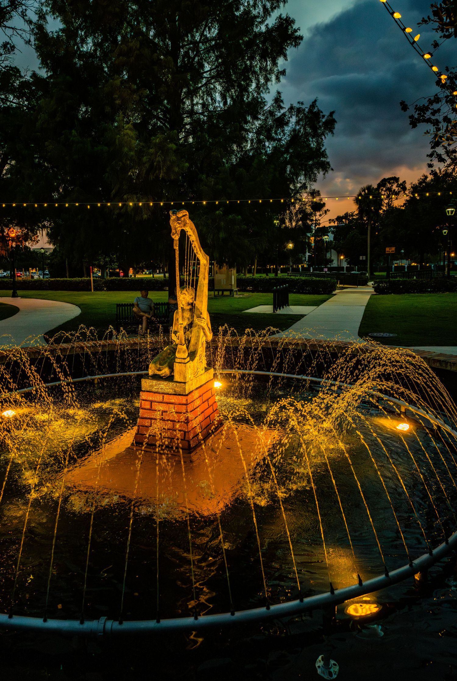 Illuminated fountain display with golden water jets against twilight sky.