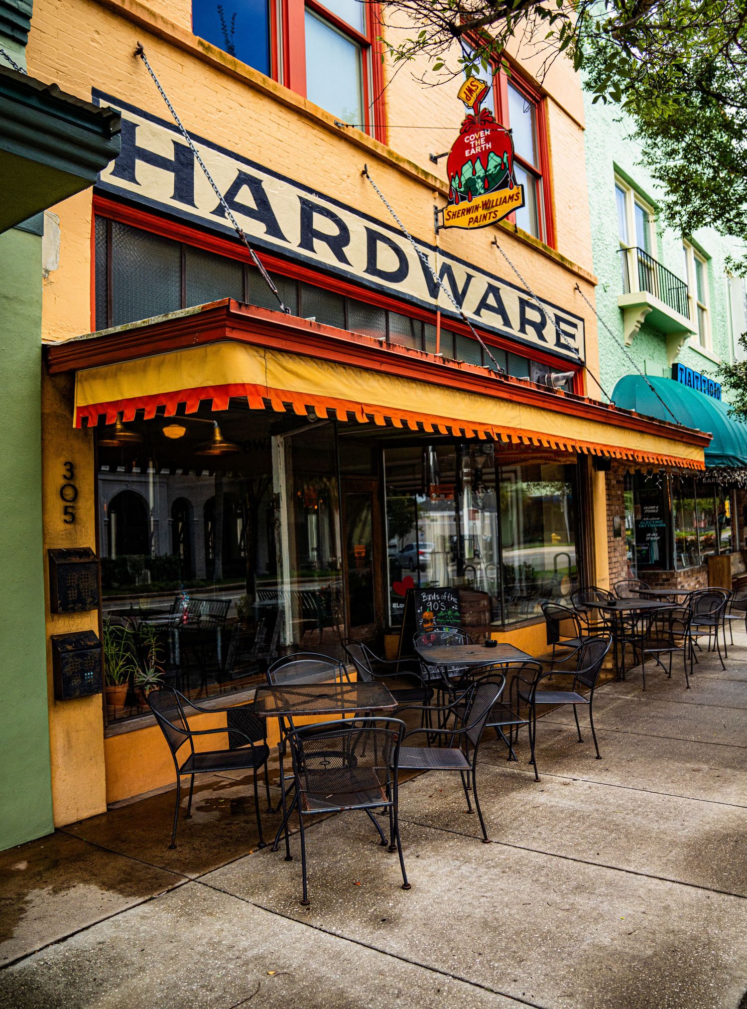 Street view of hardware store and shops with outdoor seating areas.