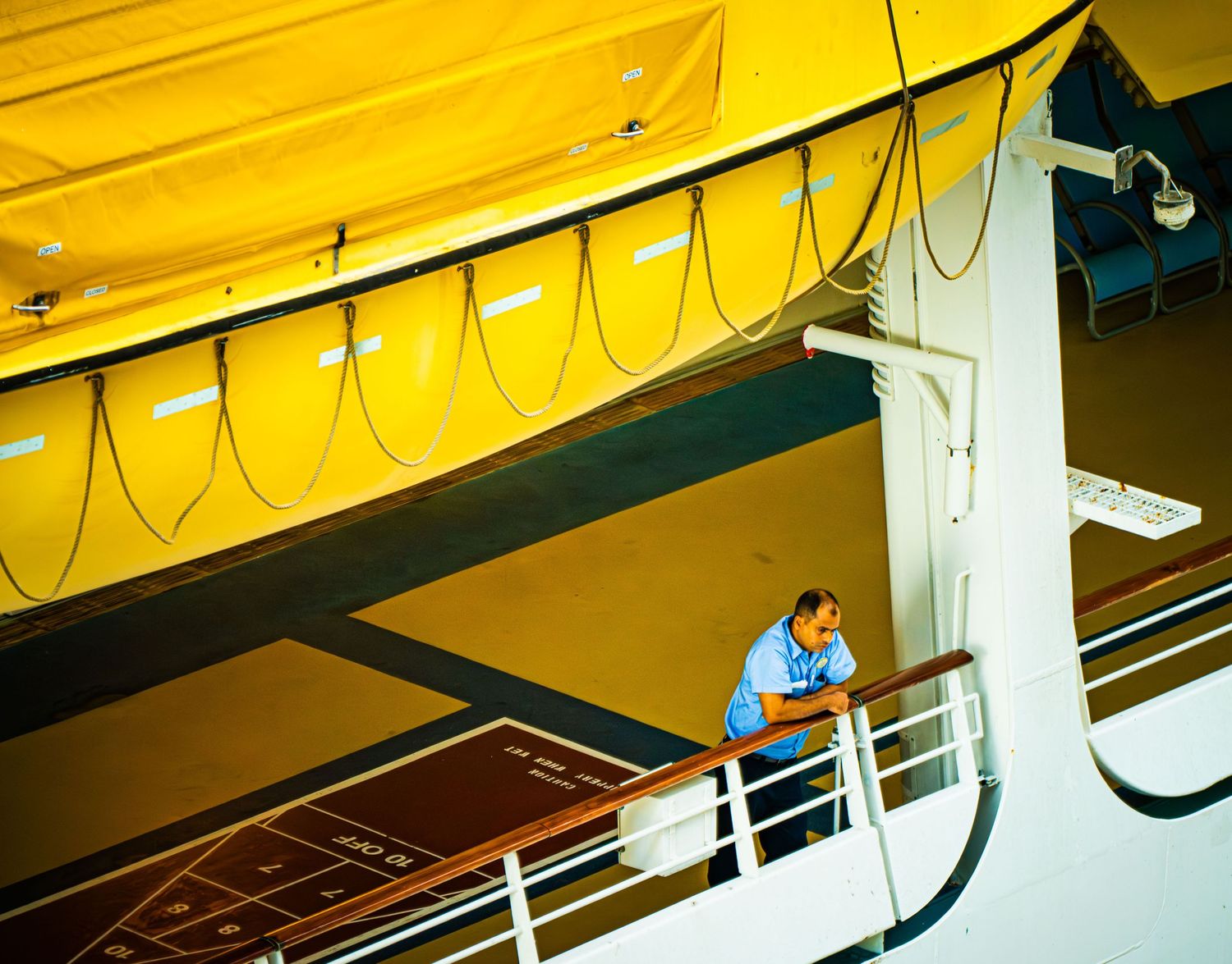 Technicians work on electrical wiring and equipment mounted to a yellow-lit industrial ceiling.