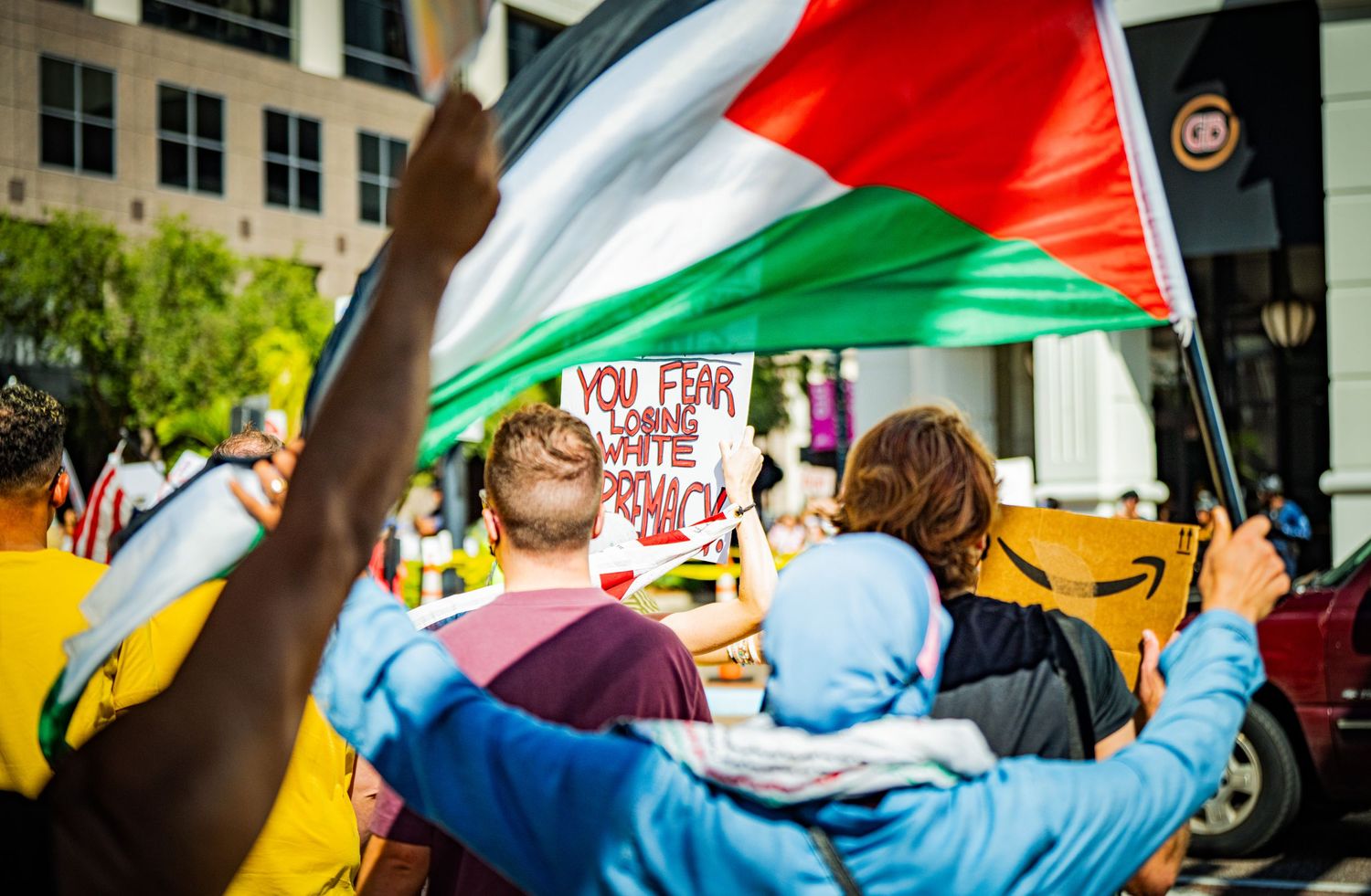Colorful flags wave in the air during a street protest.
