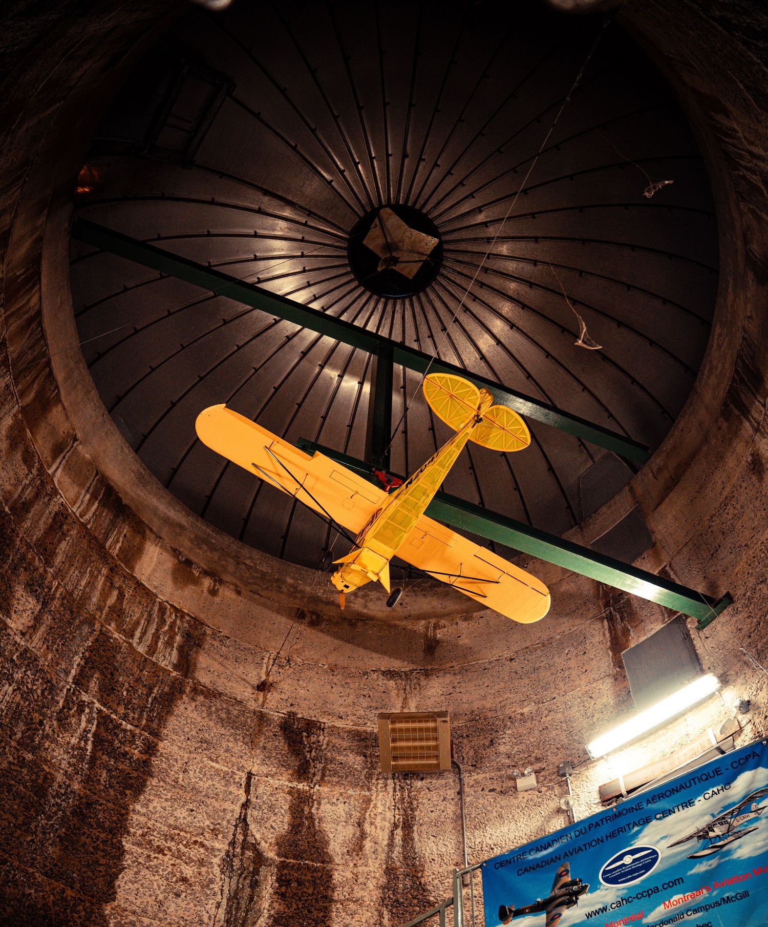 Vintage aircraft models displayed on ceiling of circular brick room with dramatic lighting.