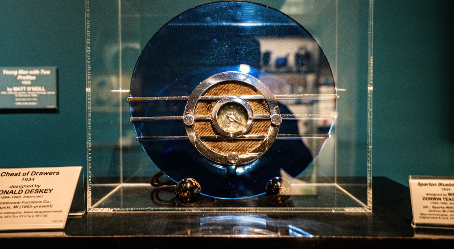 Museum display cases showcase ancient artifacts and relics under dramatic lighting in a darkened gallery.
