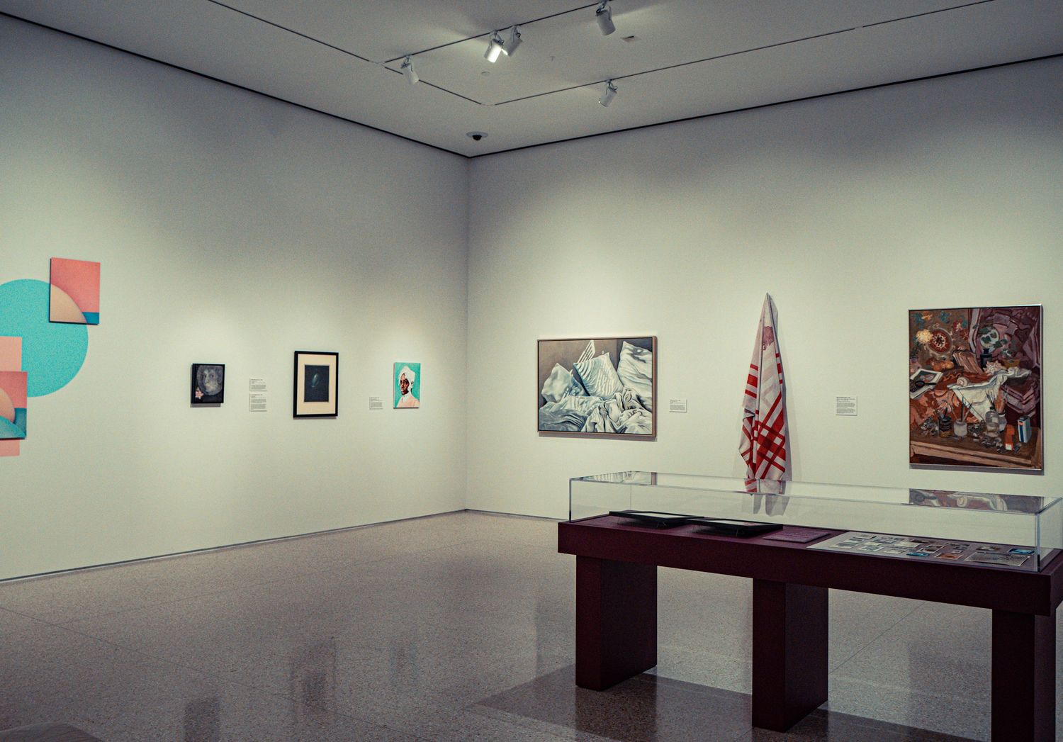 Museum exhibition space featuring various artworks and display cases arranged in a clean, modern interior.