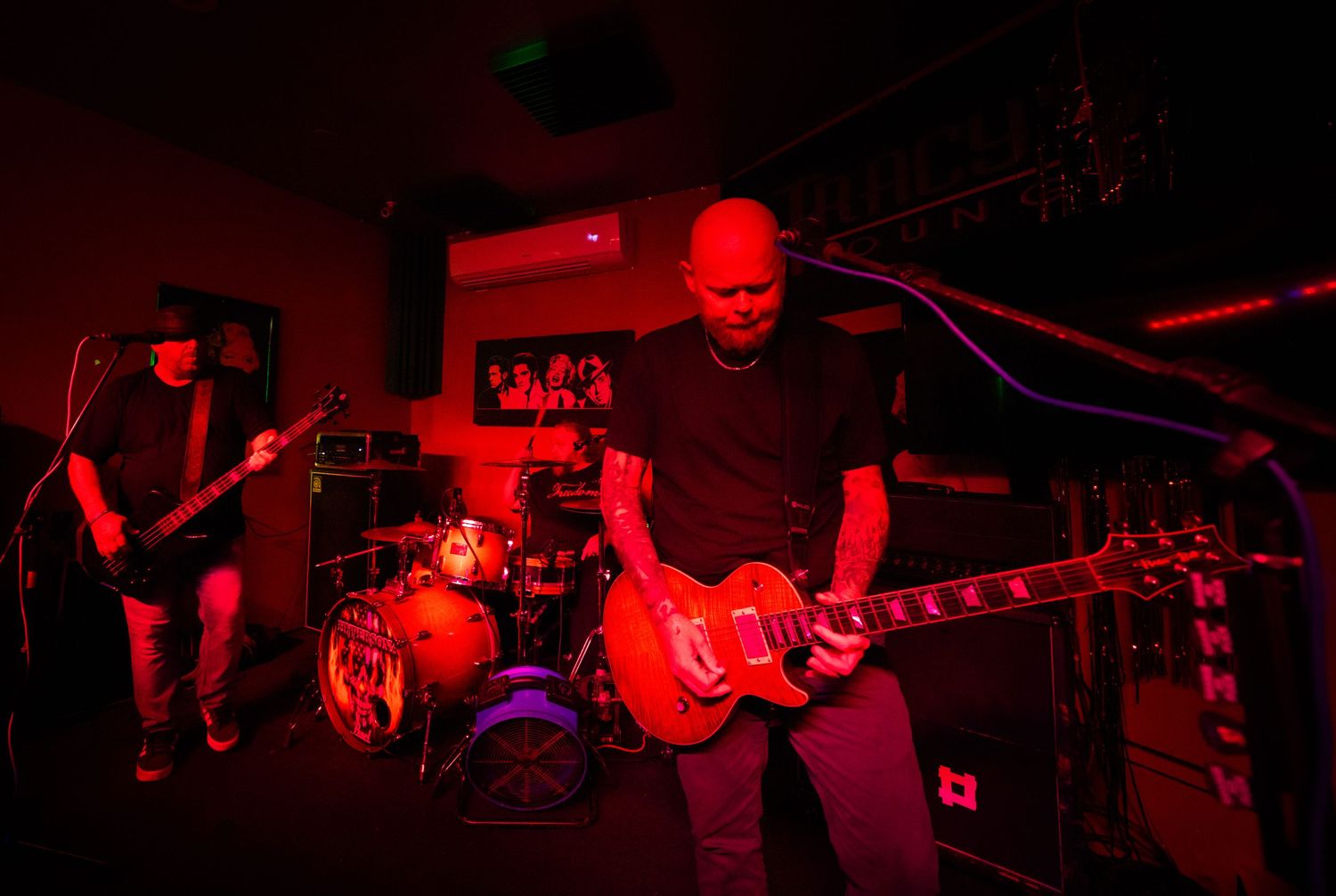 Rock concert scene with dramatic red lighting illuminating performers on stage.