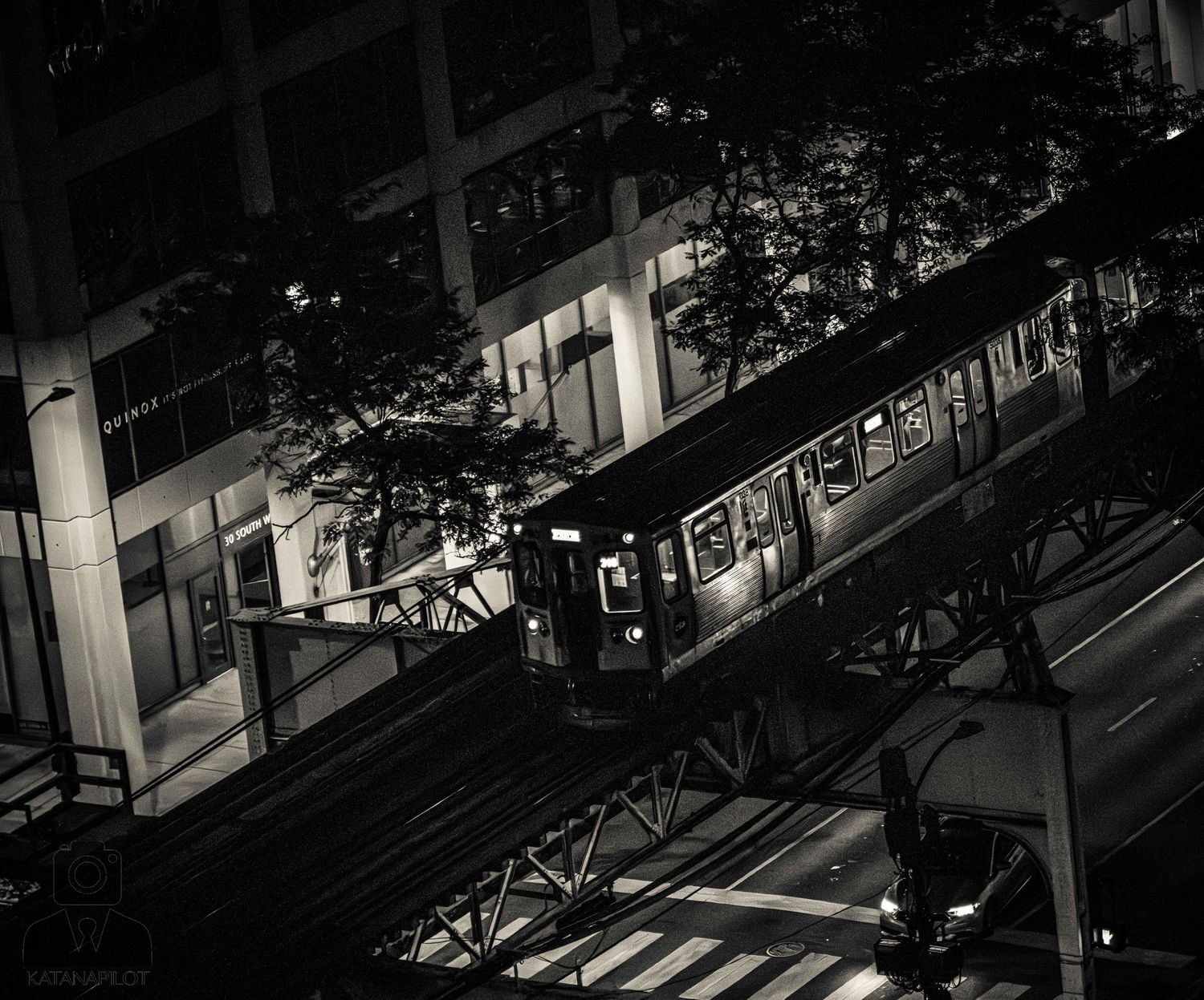Dark urban street scene with illuminated buildings and walkways at night.