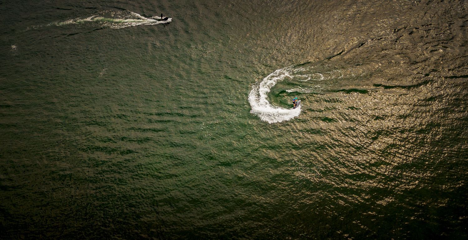 Aerial shot of speedboats leaving white trails across dark waters.