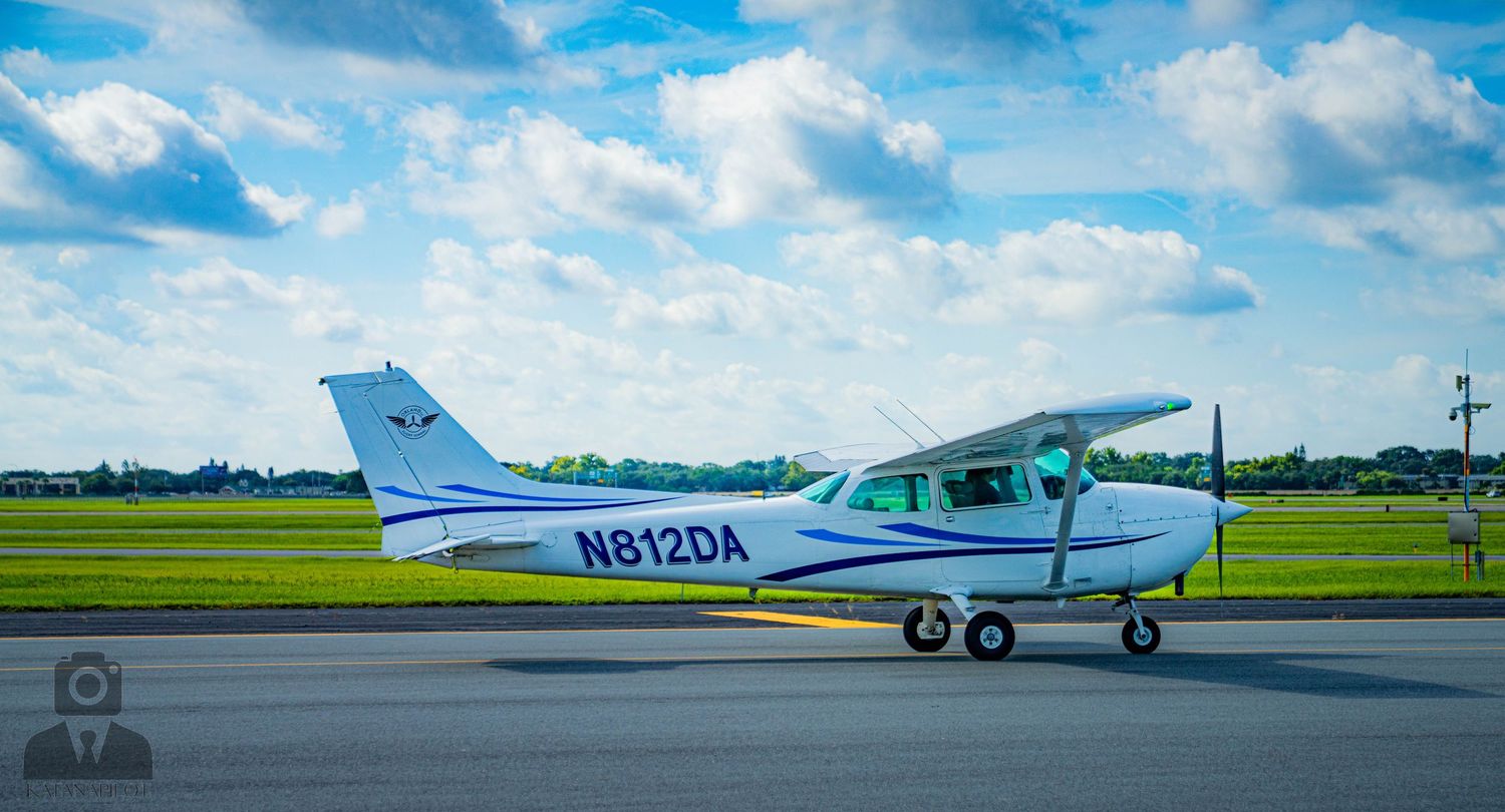 A white Cessna aircraft parked on tarmac with tail number N8129A visible under blue skies.