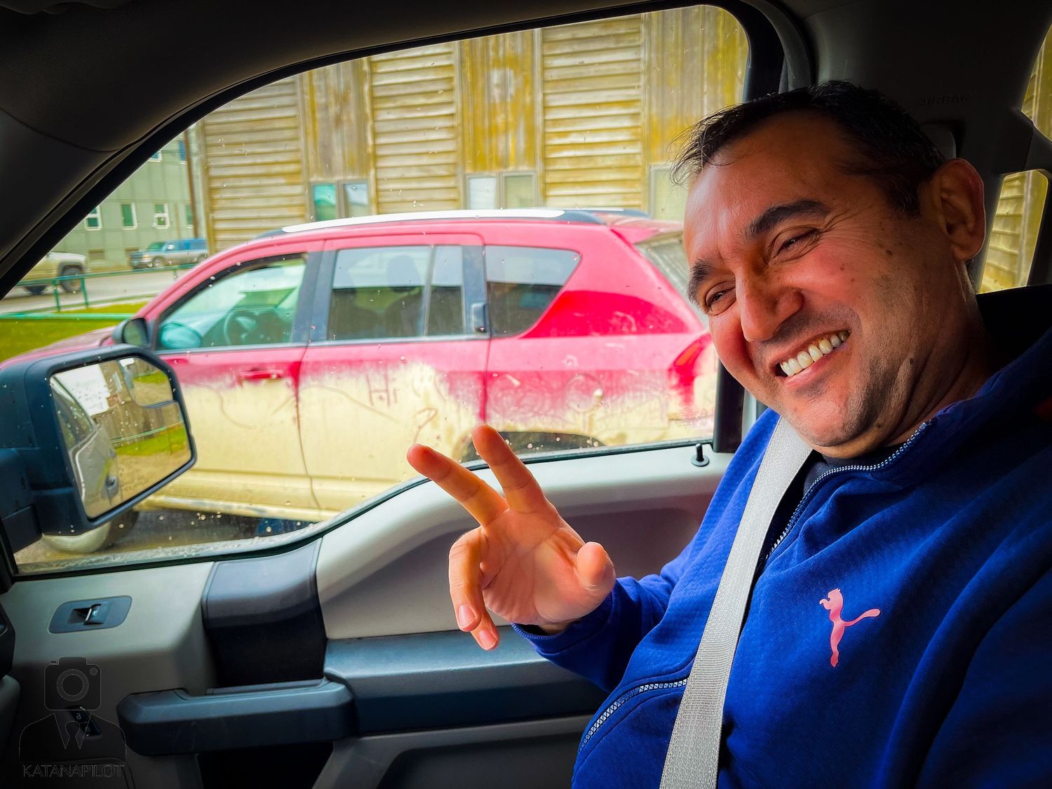 Interior view of vehicles with passengers showing peace signs through car windows.