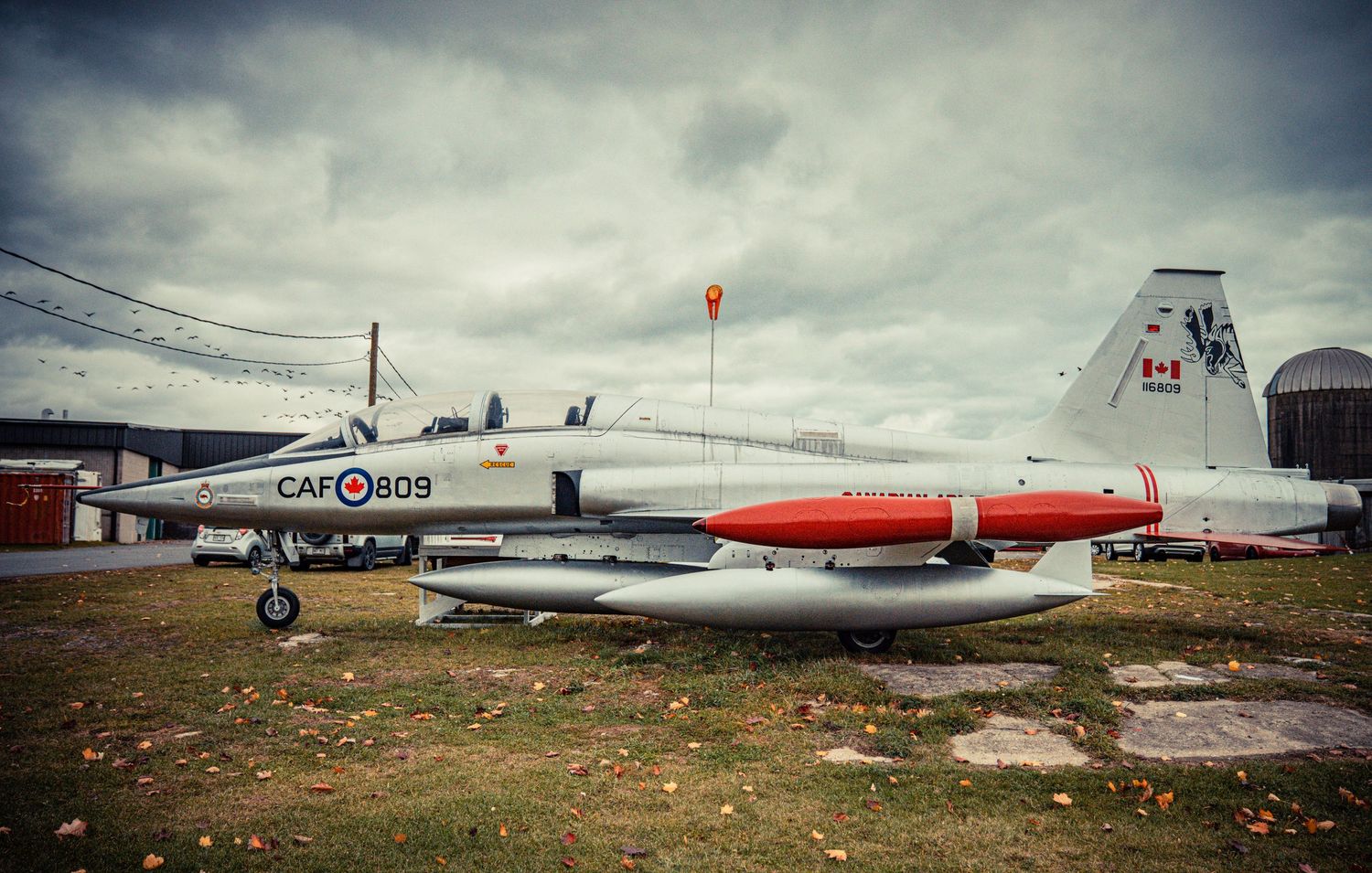 Panoramic view of parked aircraft and industrial buildings under overcast sky.