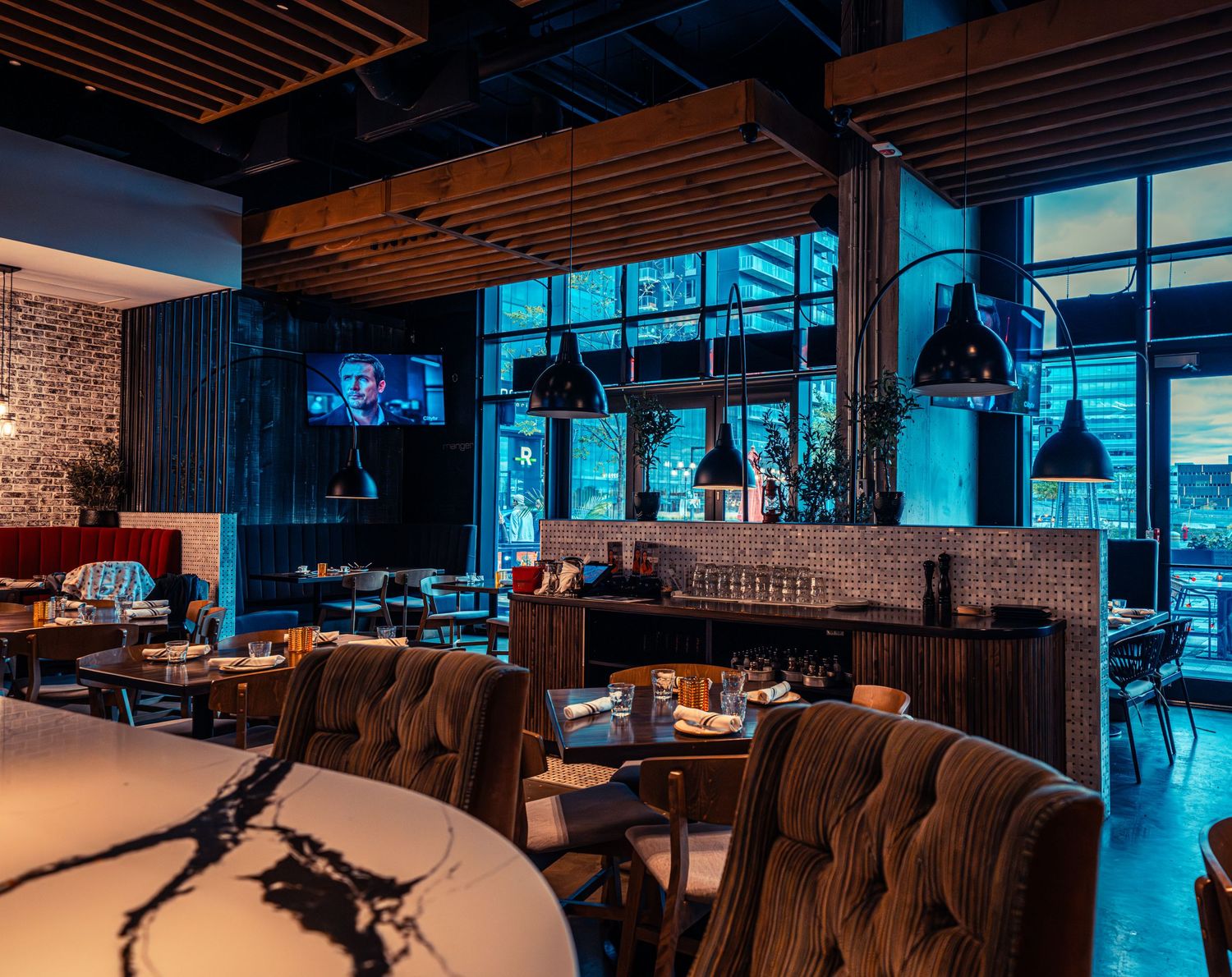 Contemporary dining space with blue ambient lighting and wooden ceiling details.