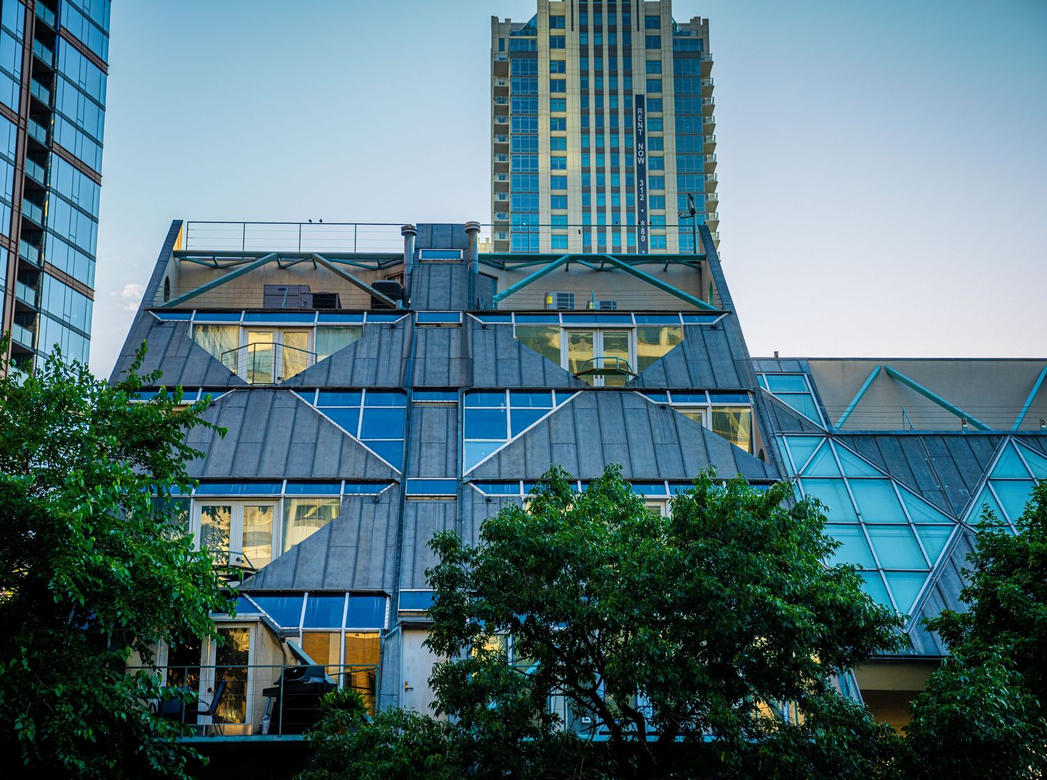 Modern glass skyscrapers reflect sunlight against a bright blue sky in an urban cityscape.