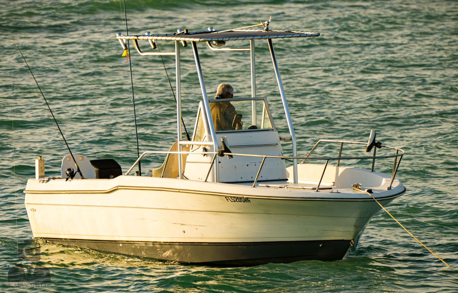 A series of fishing boats cruising through choppy green waters on a bright day.