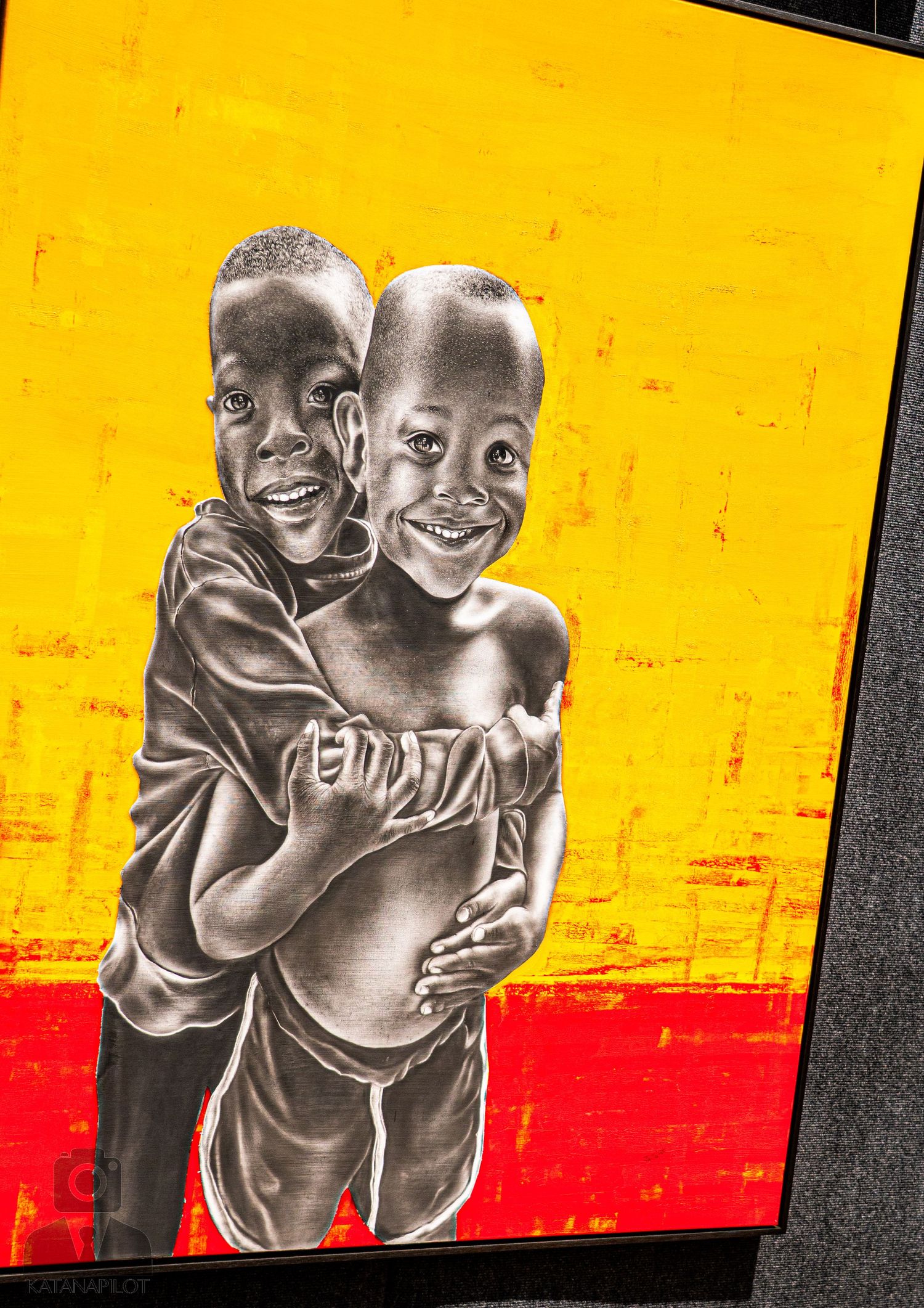 Black and white portraits mounted on vibrant yellow and red background panels in an exhibition.