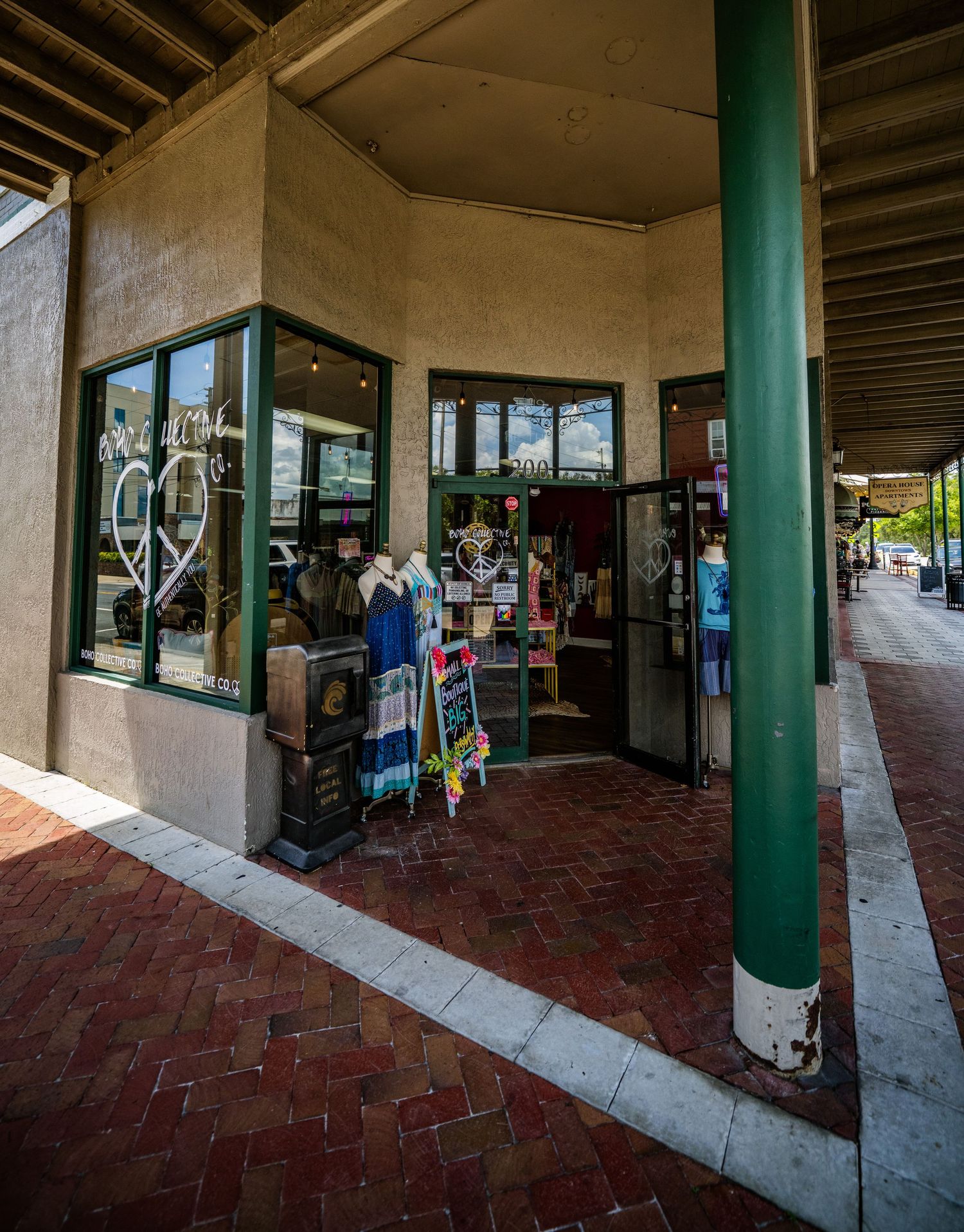Covered shopping arcade with brick flooring and green support columns.